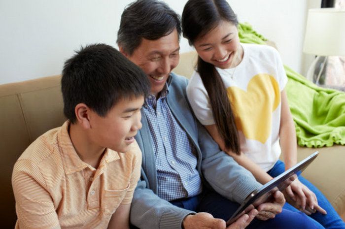 A family sitting on their couch, looking at a Made By Google tablet