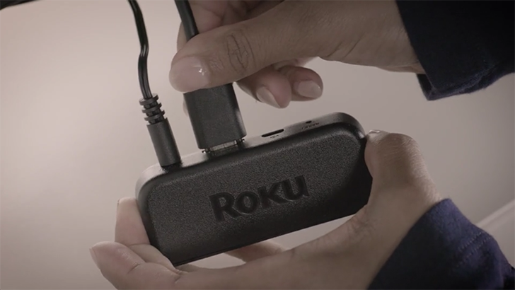 A person connecting wires to the Roku Express