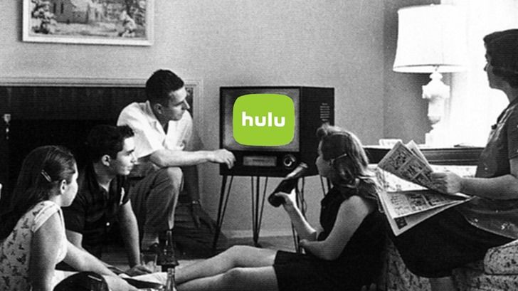 A black and white photo of a family from the 1950s sitting around a television with a bright green Hulu logo showing on the screen.