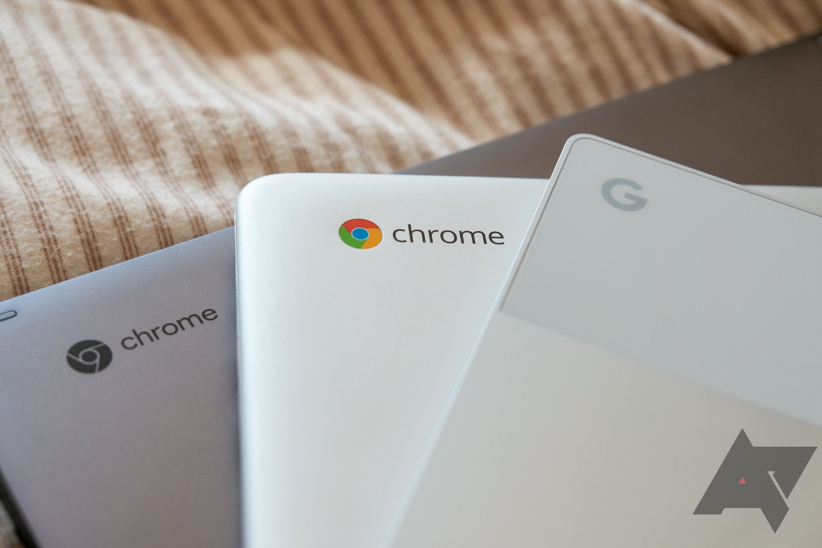 A pile of Chromebooks with the Google and ChromeOS logo