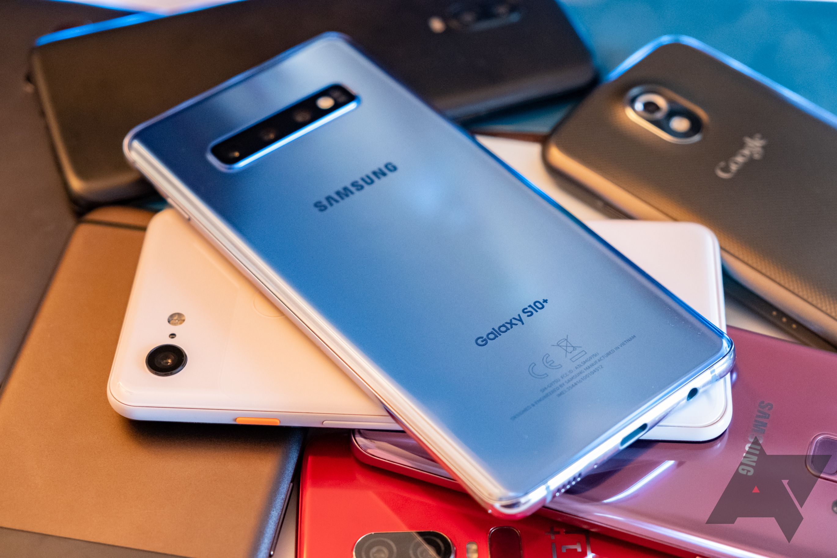 A Samsung Galaxy S10 Plus on a pile of other phones