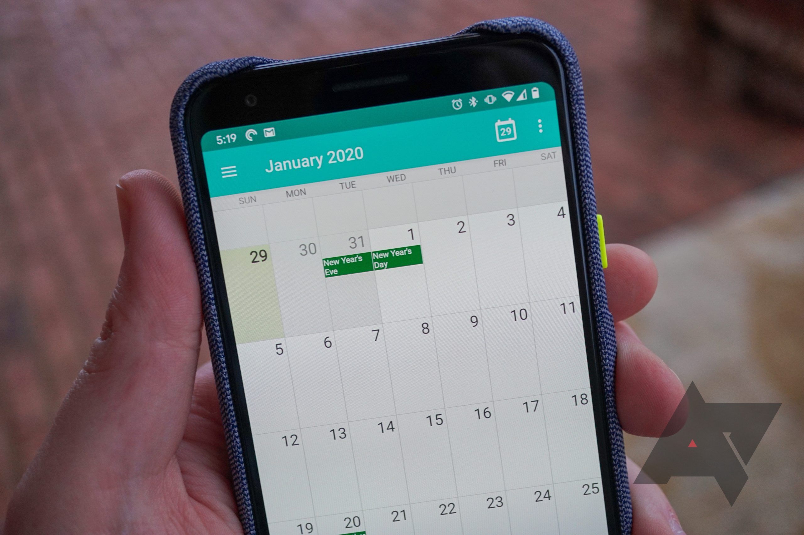 A person holds a phone with a calendar app open. 