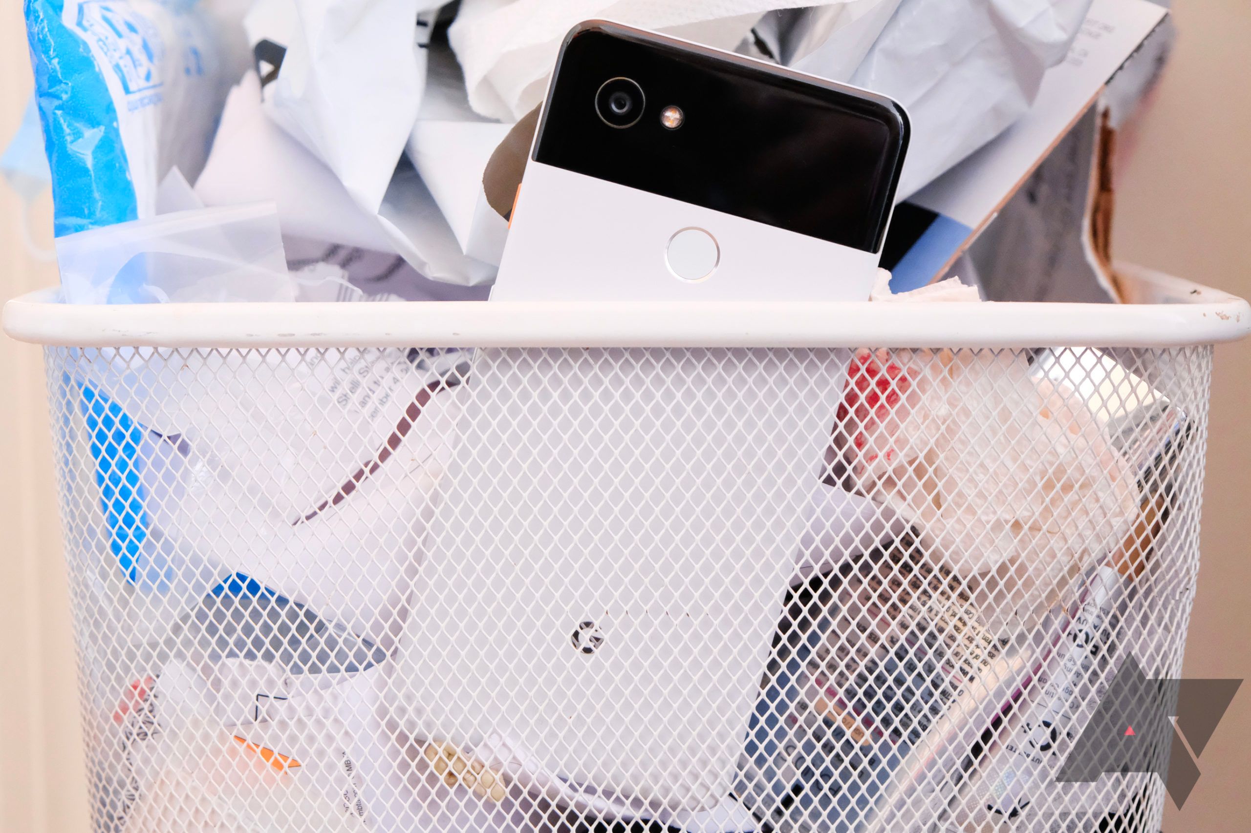 A black and white Google Pixel 2 in a mesh metal waste bin
