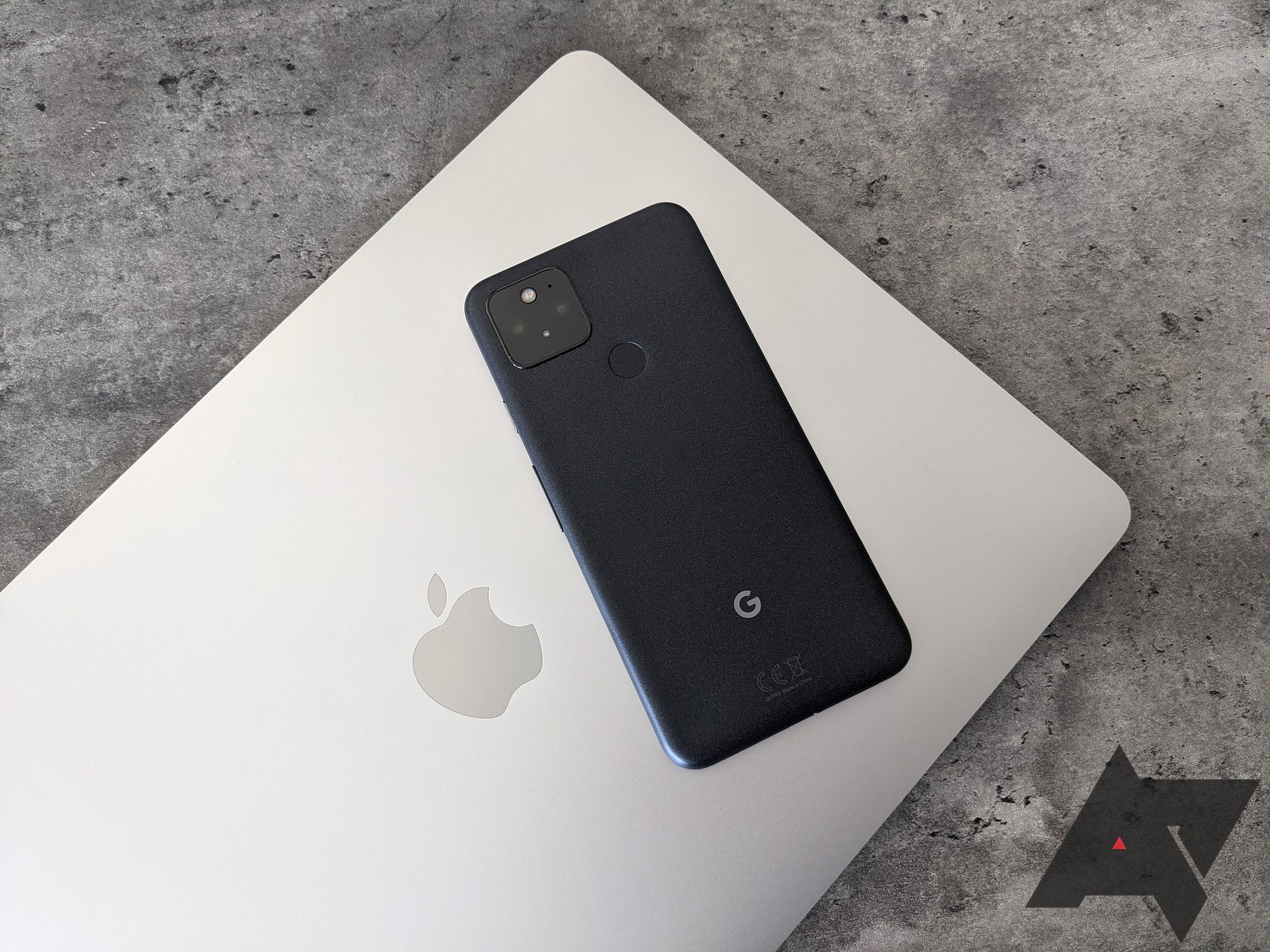 A Google Pixel smartphone sits on top of a silver Apple MacBook Air