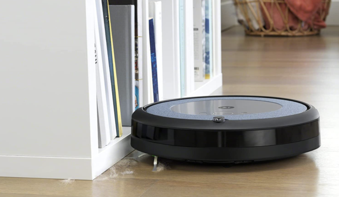 Roomba vacuum picking up hair against a bookcase