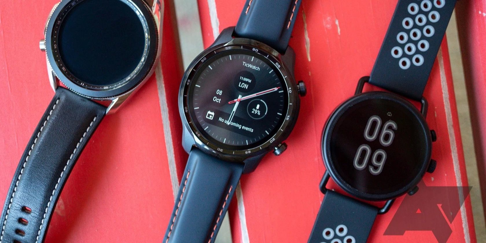 Three smartwatches on a red bench.