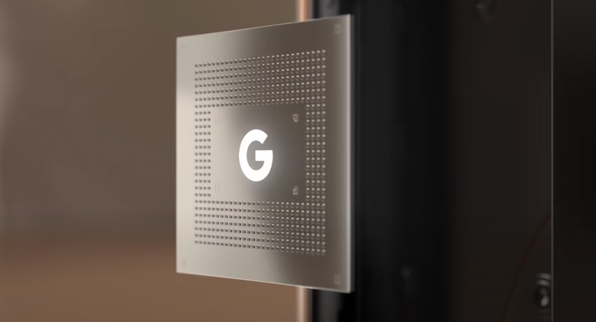 A representation of the Google Tensor chip with a G logo on it, floating in front of a blurred out background