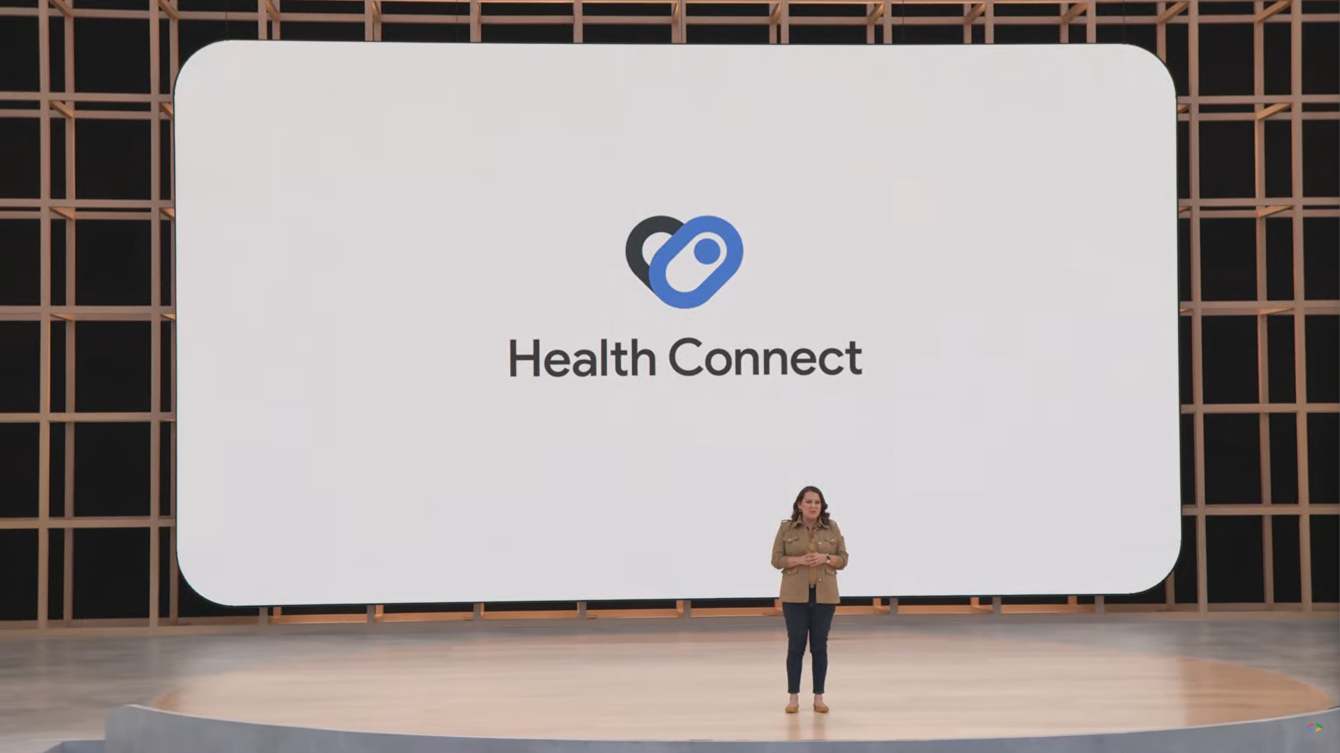 A person is standing on stage during Google I/O in front of a big screen with the words 