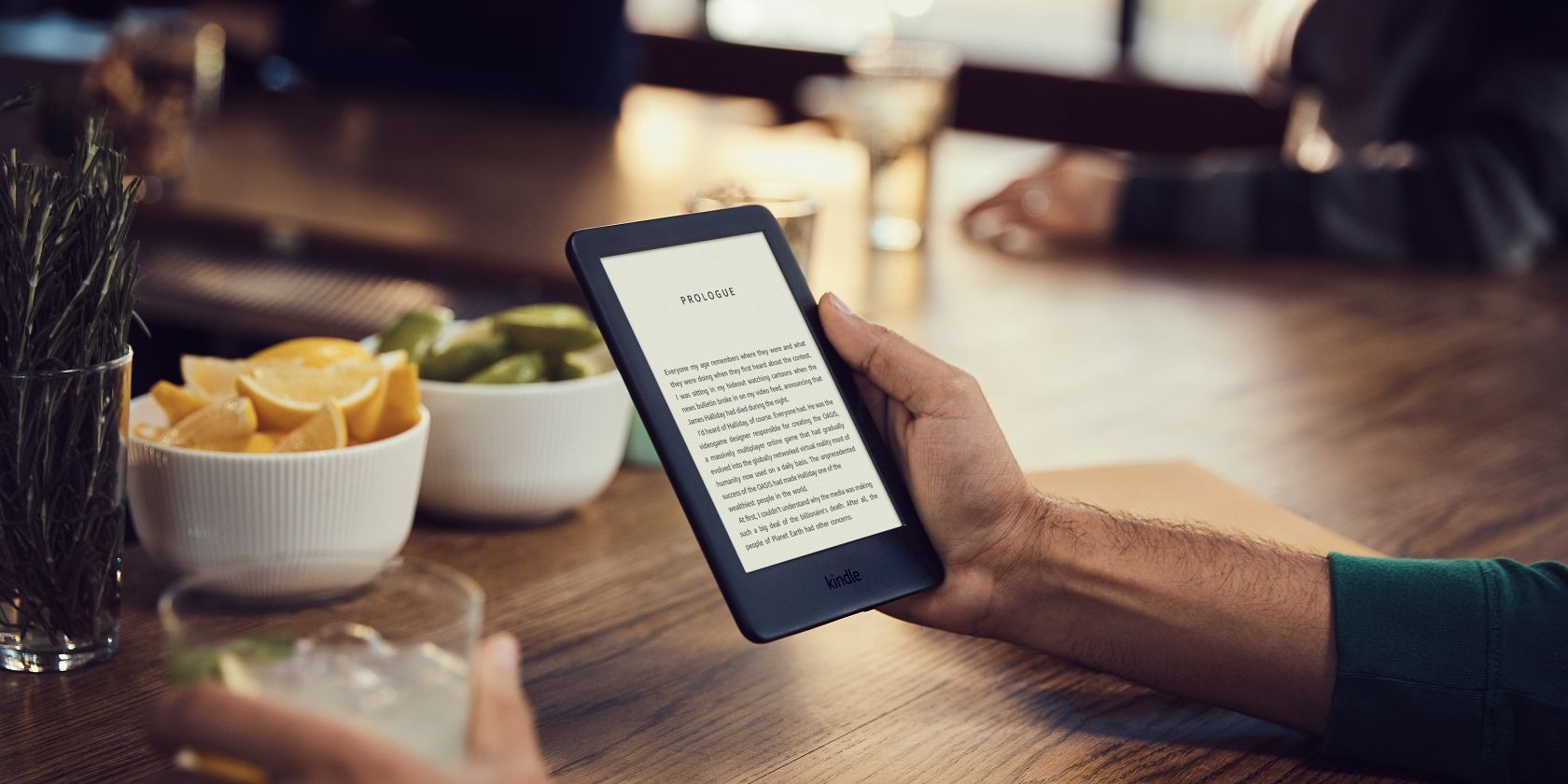 A person sitting in a cafe reading a book on a Kindle.