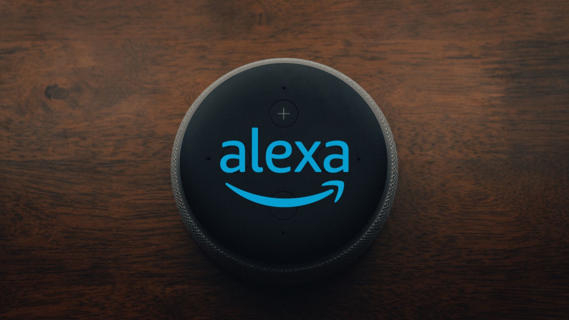 Seorang pembicara cerdas di atas meja kayu.  Logo Alexa menyala di bagian atas speaker.