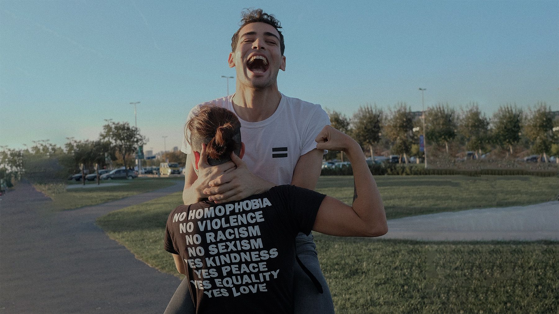 A man is joyfully jumping up and hugging another man wearing a Lockwood 51 shirt that reads 