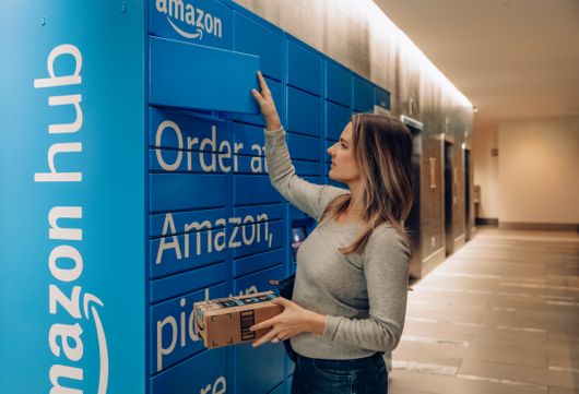 A woman pulls out an Amazon package from an Amazon locker. 