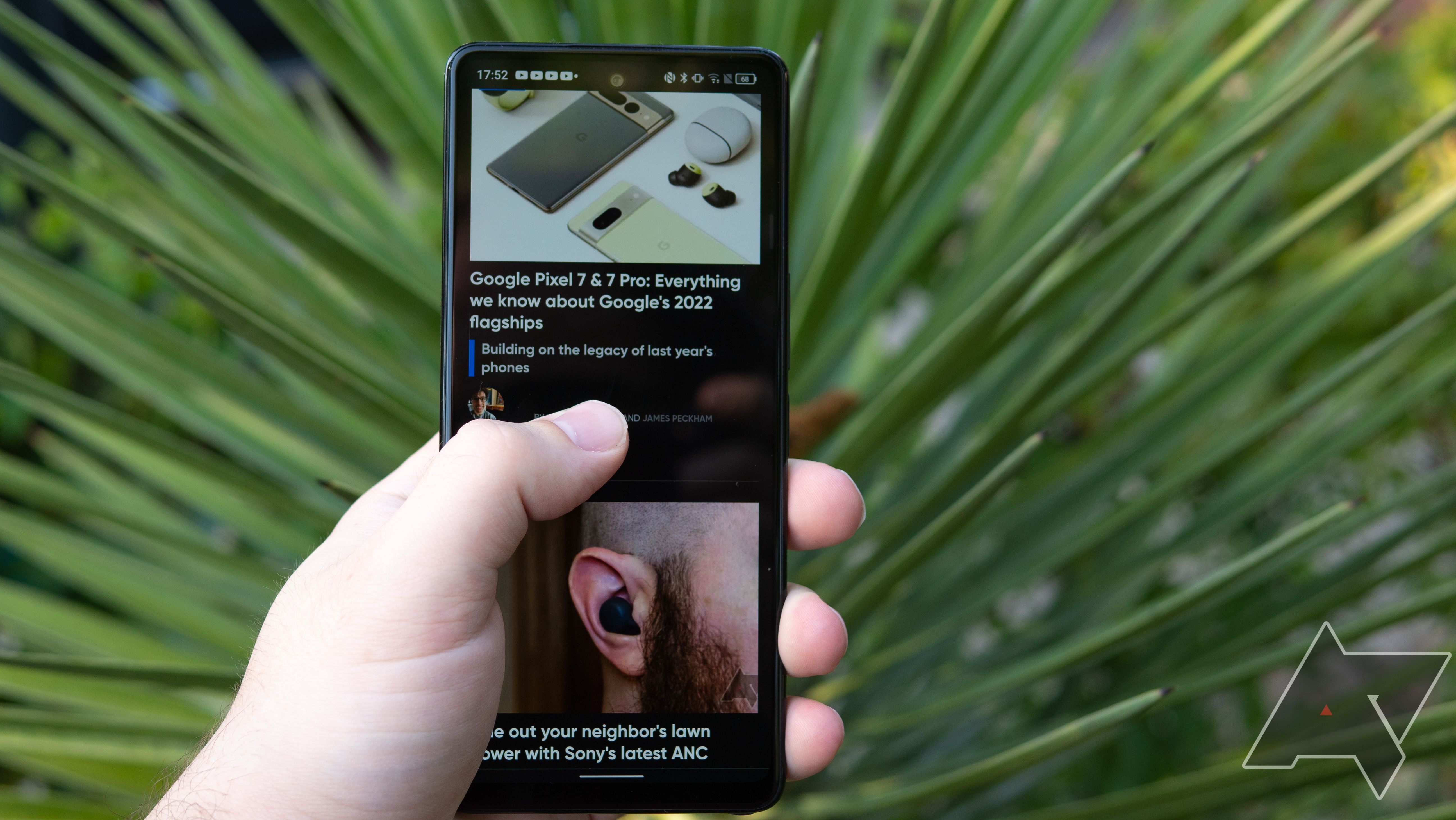 A hand holding a TCL Stylus 5G with a plant in the background