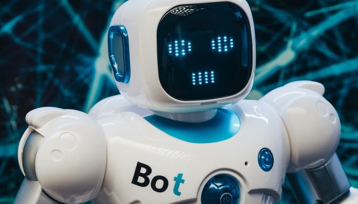 Um velho robô branco fica contra um fundo azul futurista.