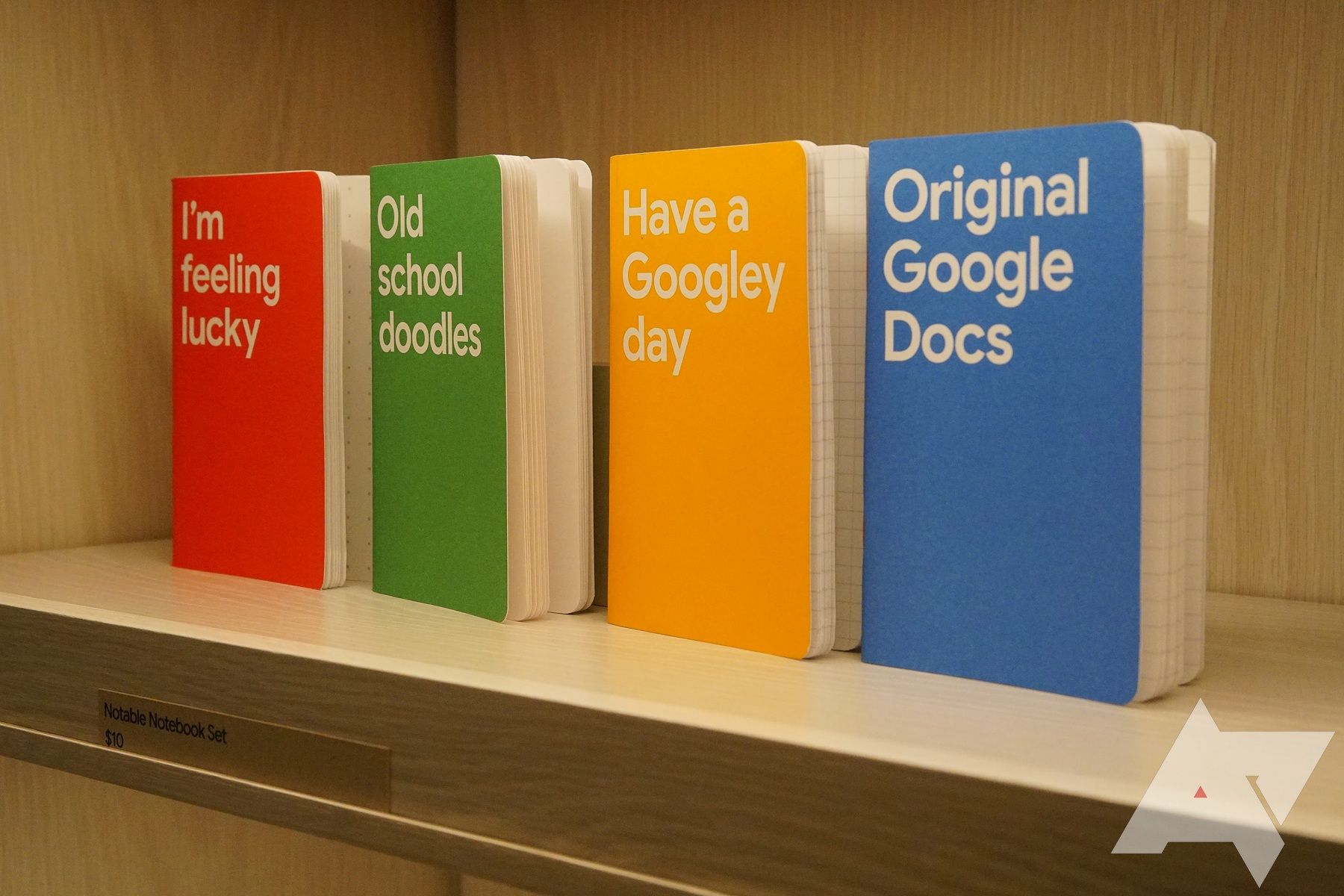 Four notebook lined up on a shelf, the last one says, 