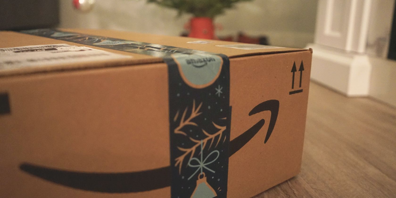 An amazon package sits in the foreground with festive decorations in the background.