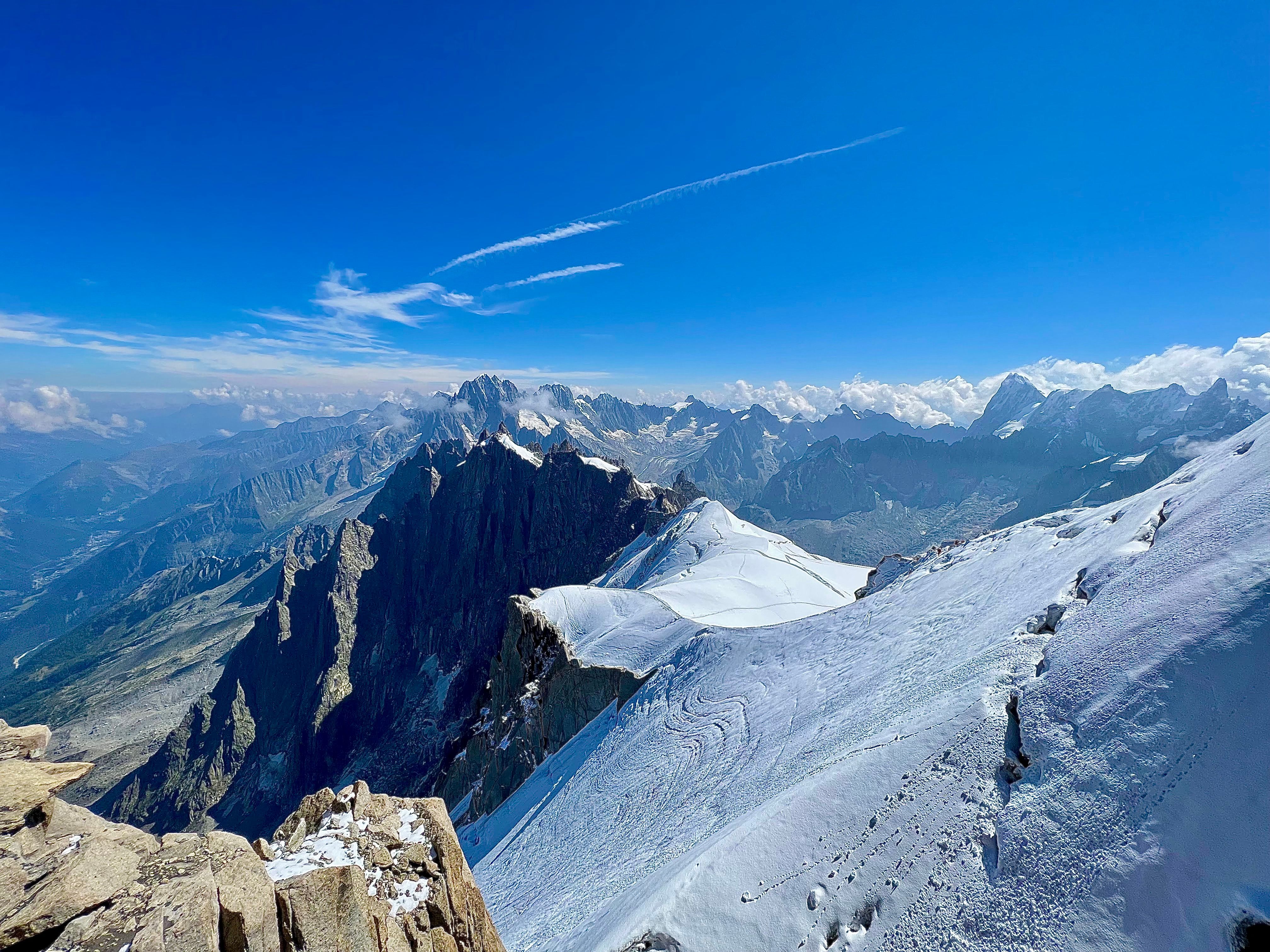 A photo on the top of a mountain with other mountains visible in the background with brighter edited colors