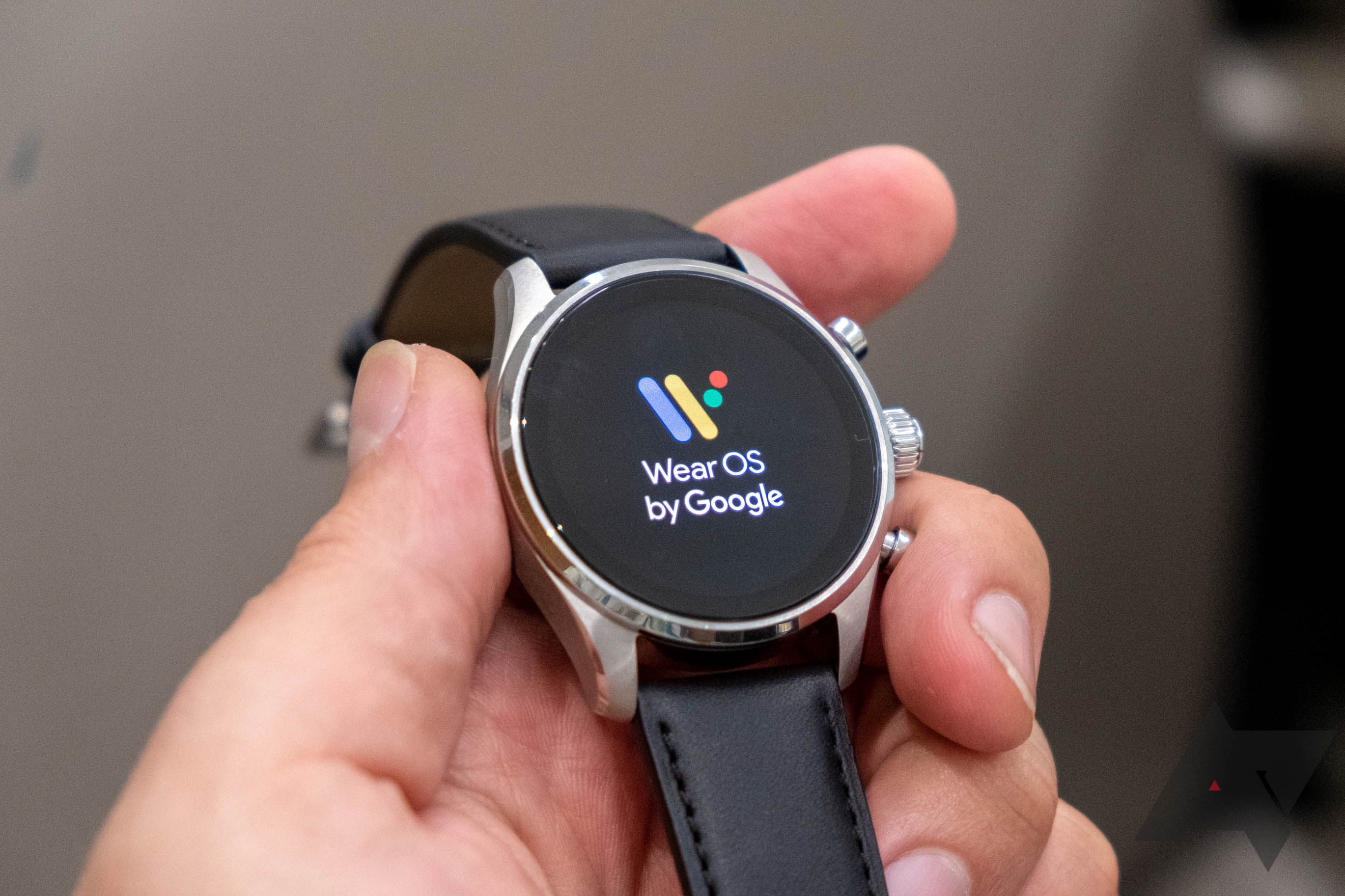 A hand holding a Montblanc Summit 3 WearOS watch with the WearOS by Google words and logo on the face