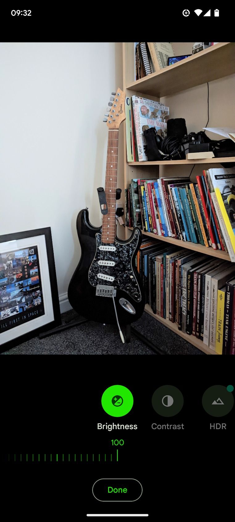black electric guitar standing next to bookshelf and picture frame