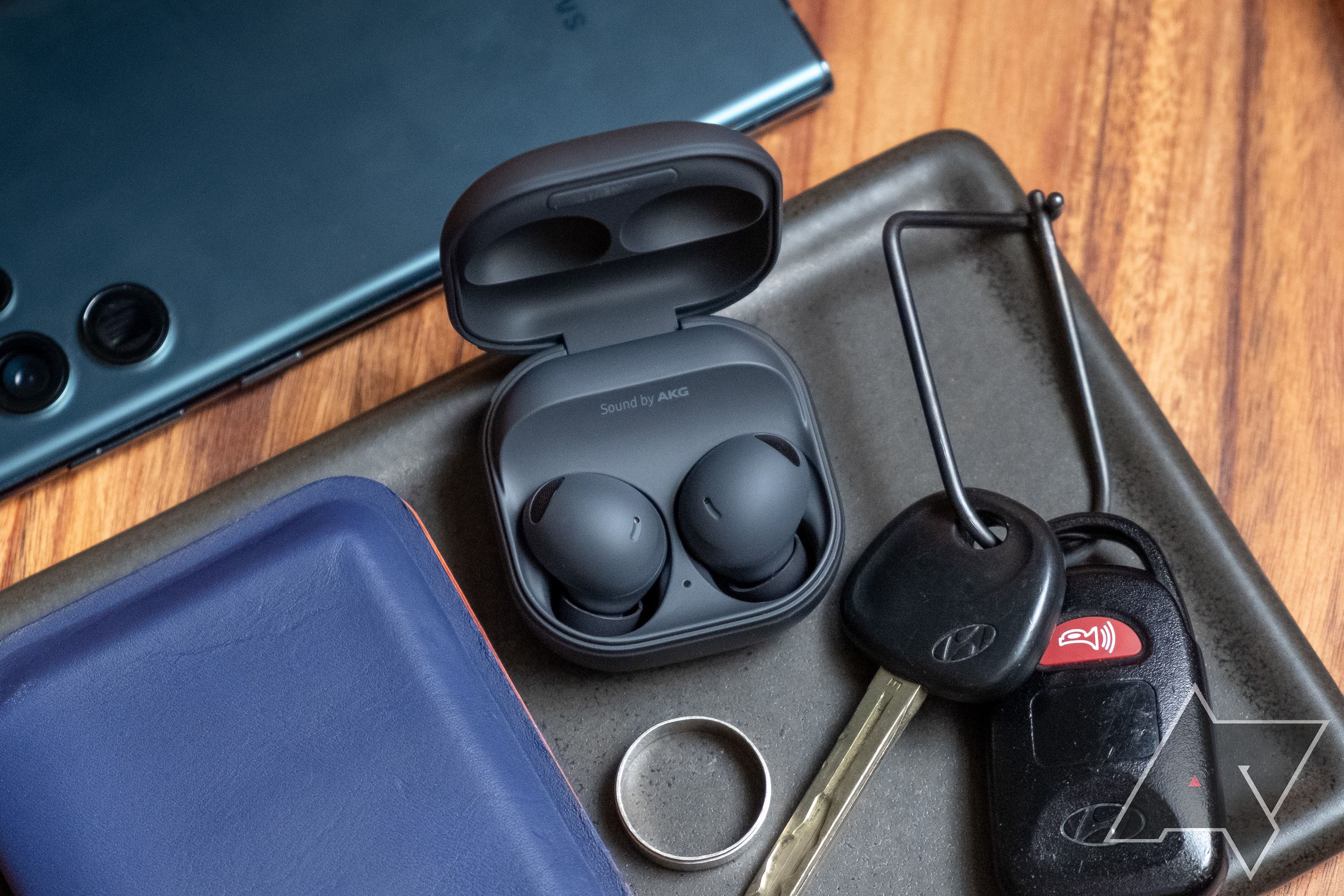 Samsung Galaxy Buds 2 Pro in a tray with some keys, a ring, and a phone.