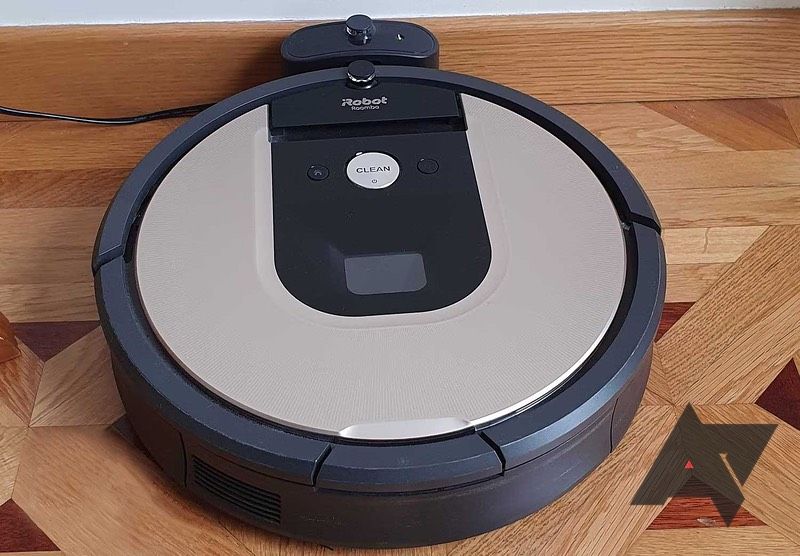 A robotic vacuum sits in its charger dock on a wood floor. 