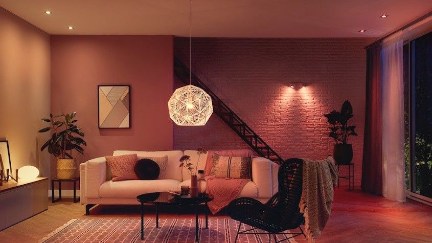 living room with a painted brick wall, sofa, chair, table and soft overhead and accent lighting. 