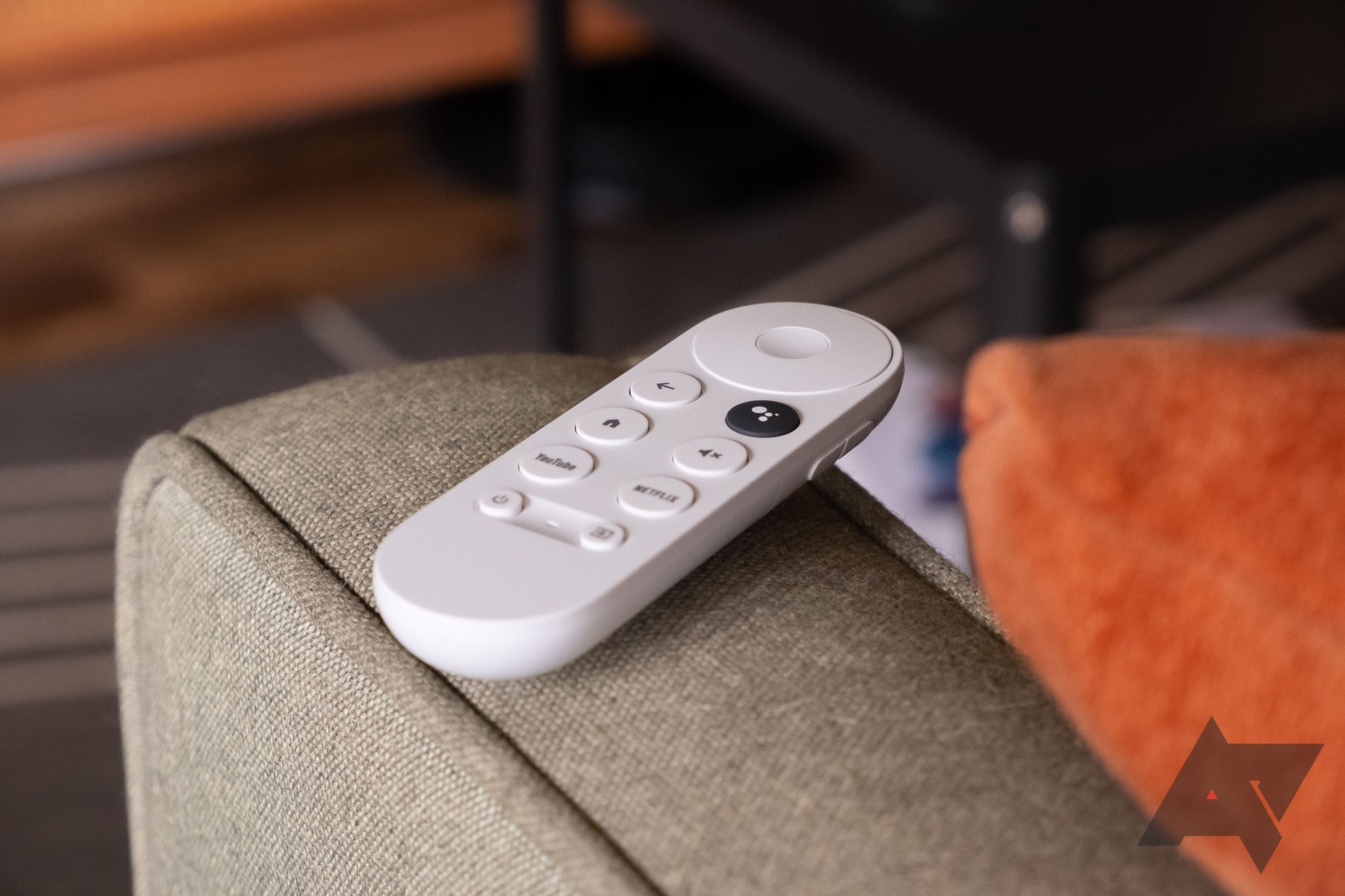 Chromecast with Google TV remote on the arm of a sofa.