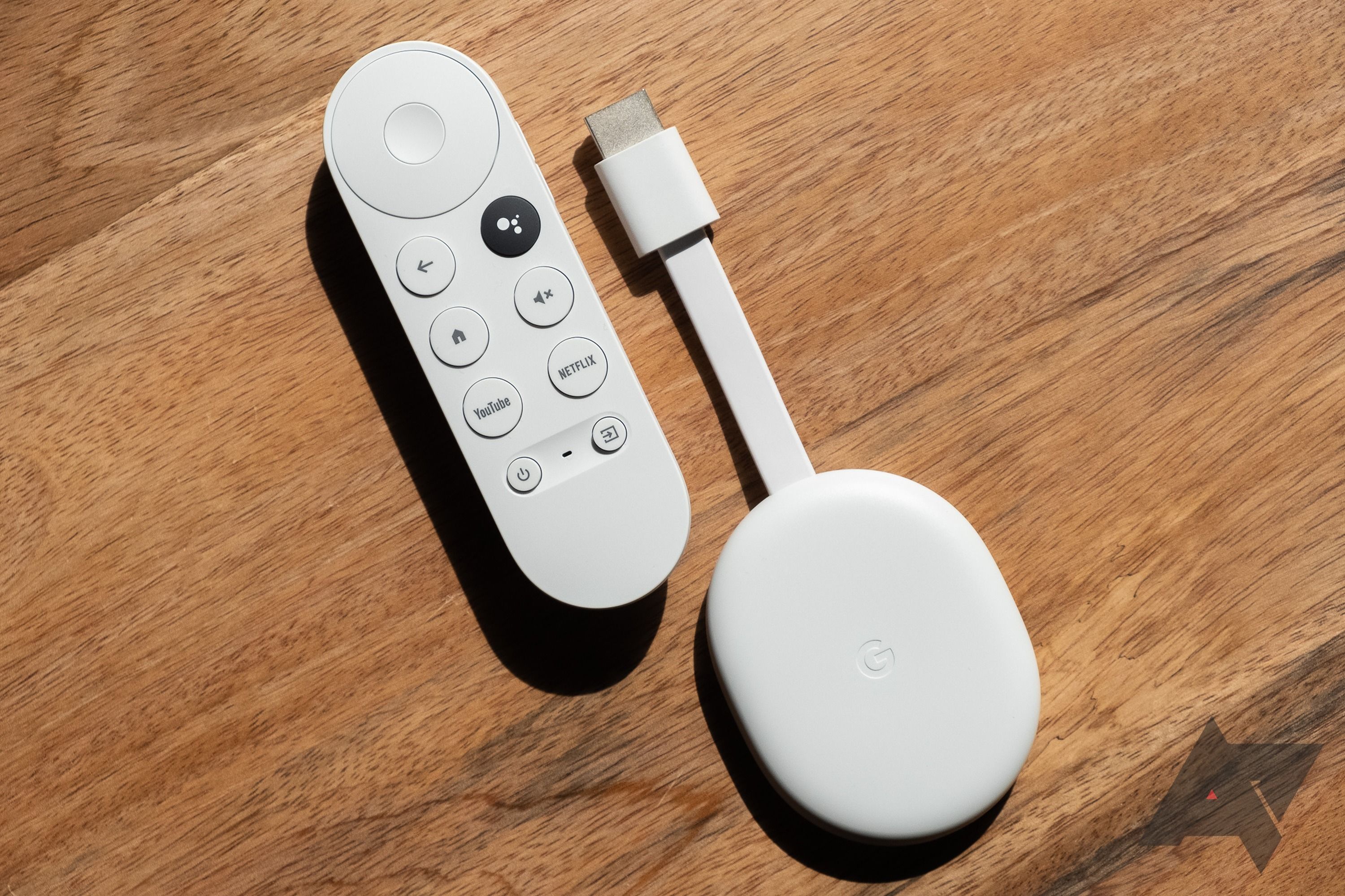 Chromecast with Google TV remote and streaming device on a wooden surface