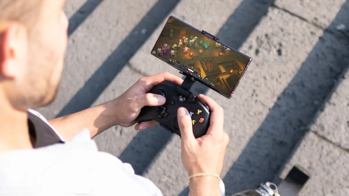 man holding an xbox controller with phone connected by a stand