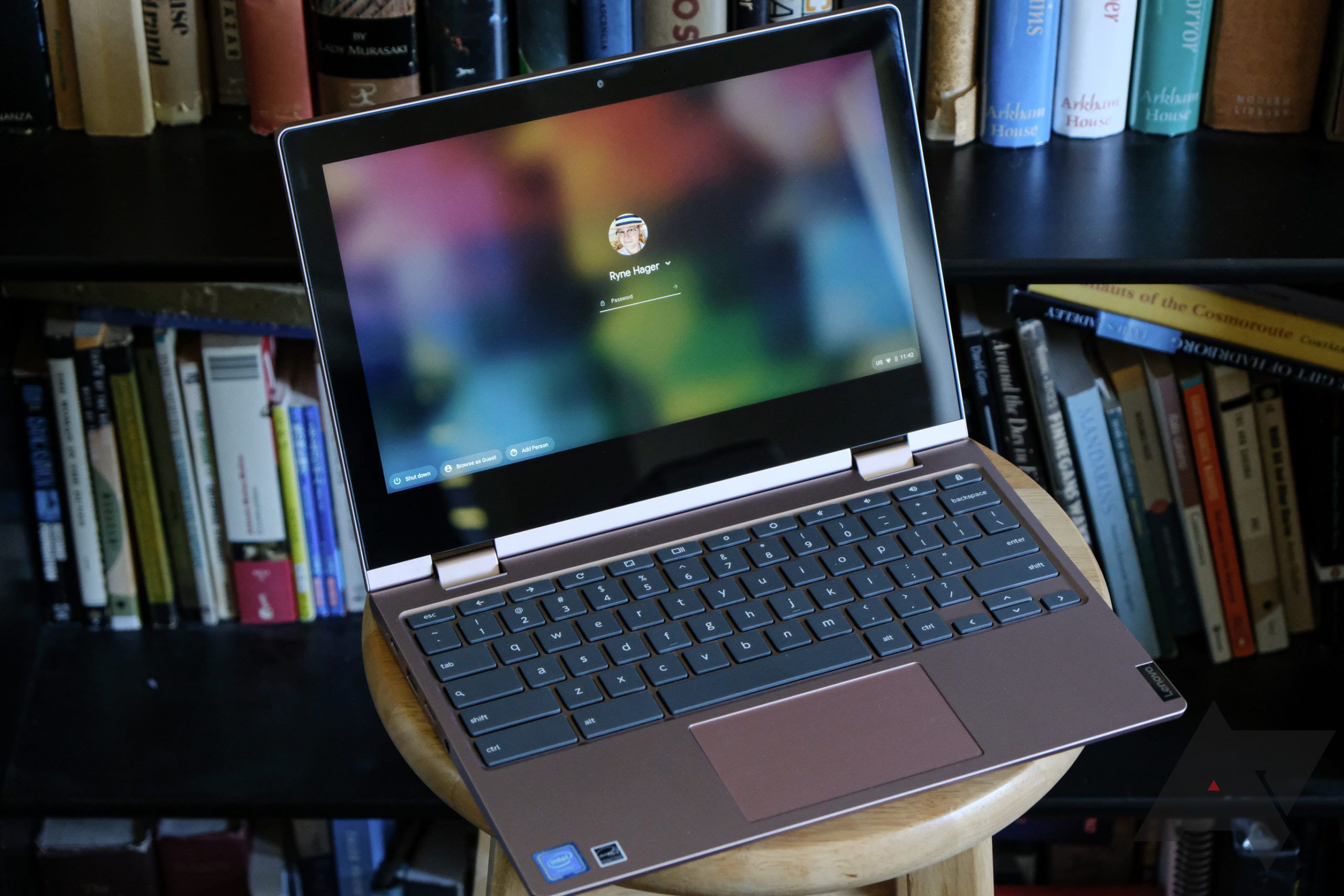 A Lenovo Flex 3 Chromebook sitting on a stool in front of a bookshelf filled with books.