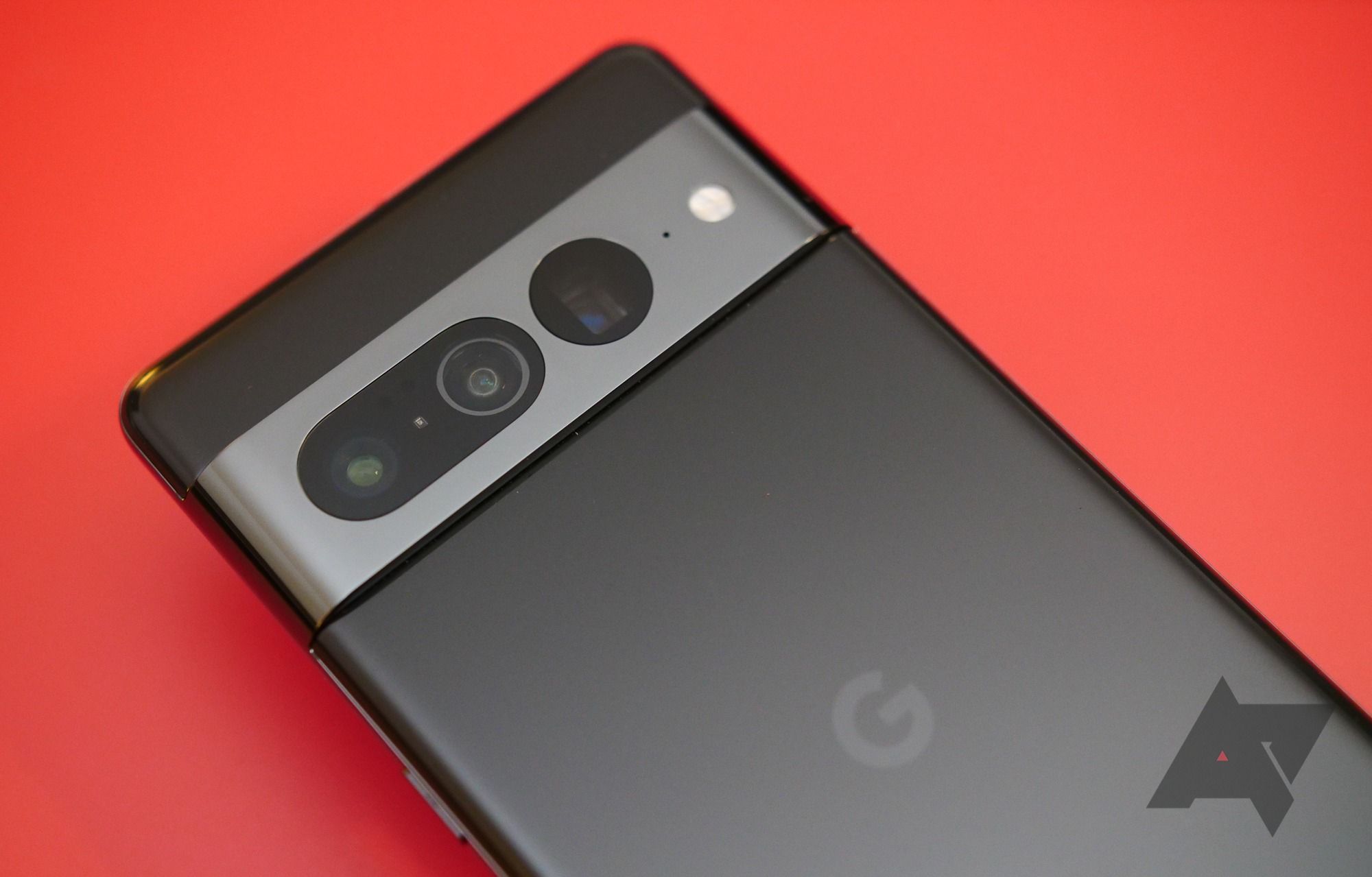 An image of a black Google Pixel 7 Pro against a red background. The silver camera bar is the focal point.