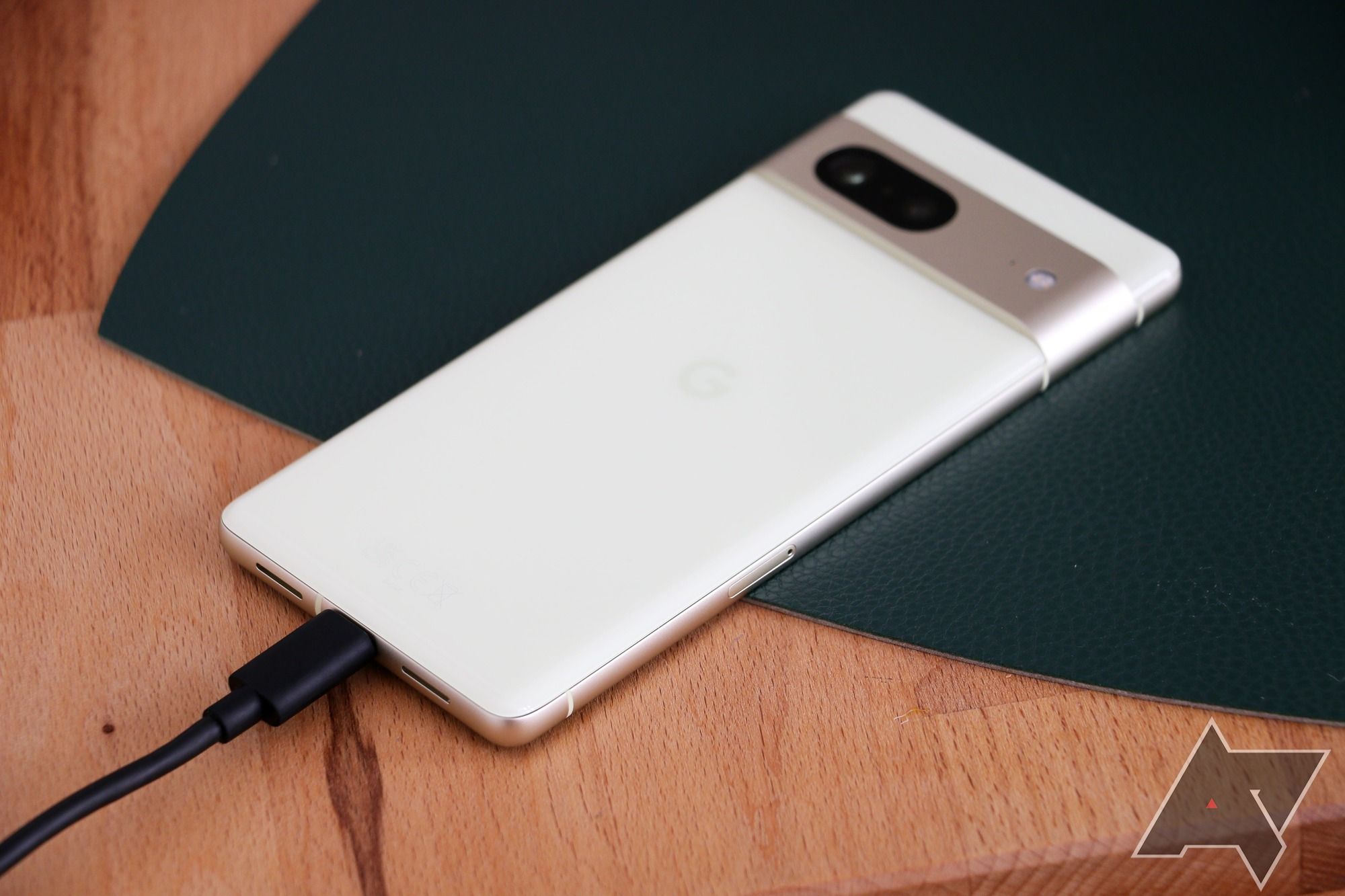 The Google Pixel 7 laying face-down with a charging cable connected to it.