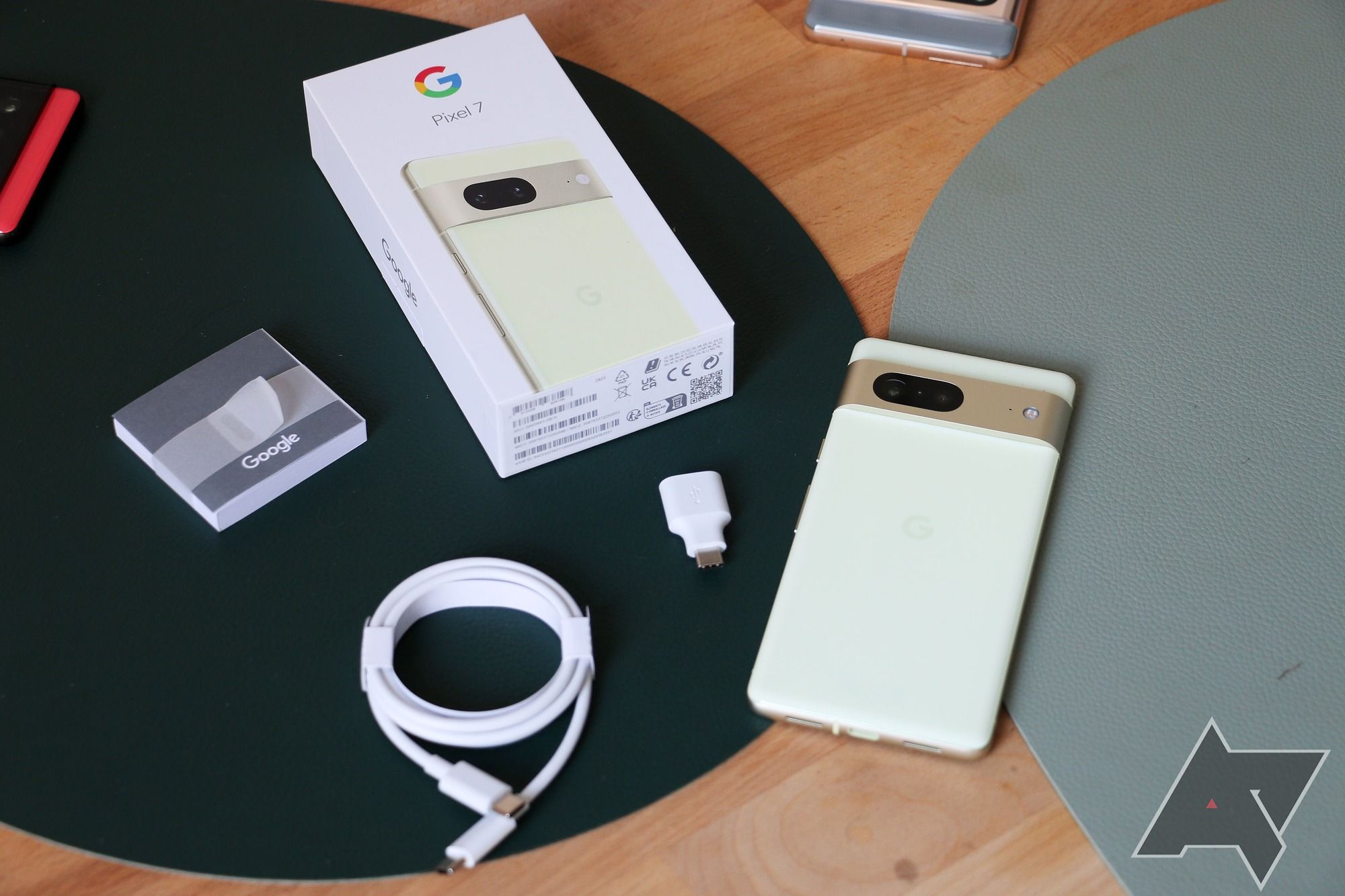 The Google Pixel 7 and the contents of its box laying spread out on a surface.