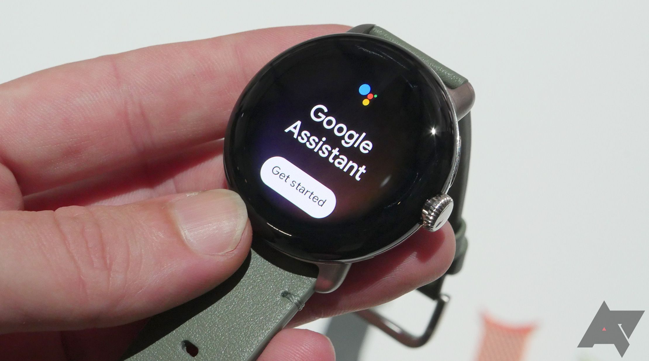 A hand holding a Google Pixel watch showing Google Assistant