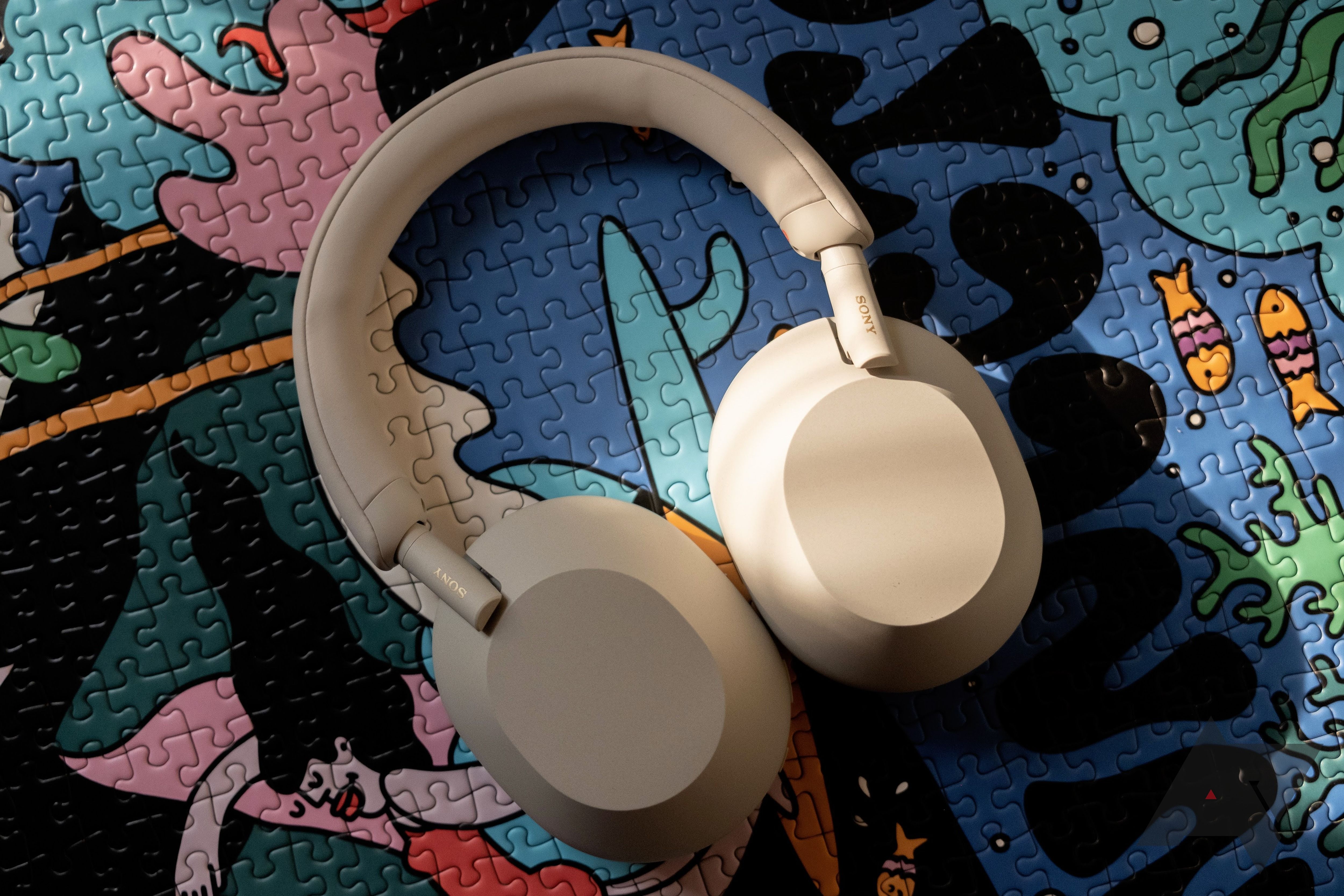 White Sony WH-1000XM5 headphones laying on top of a colorful puzzle.