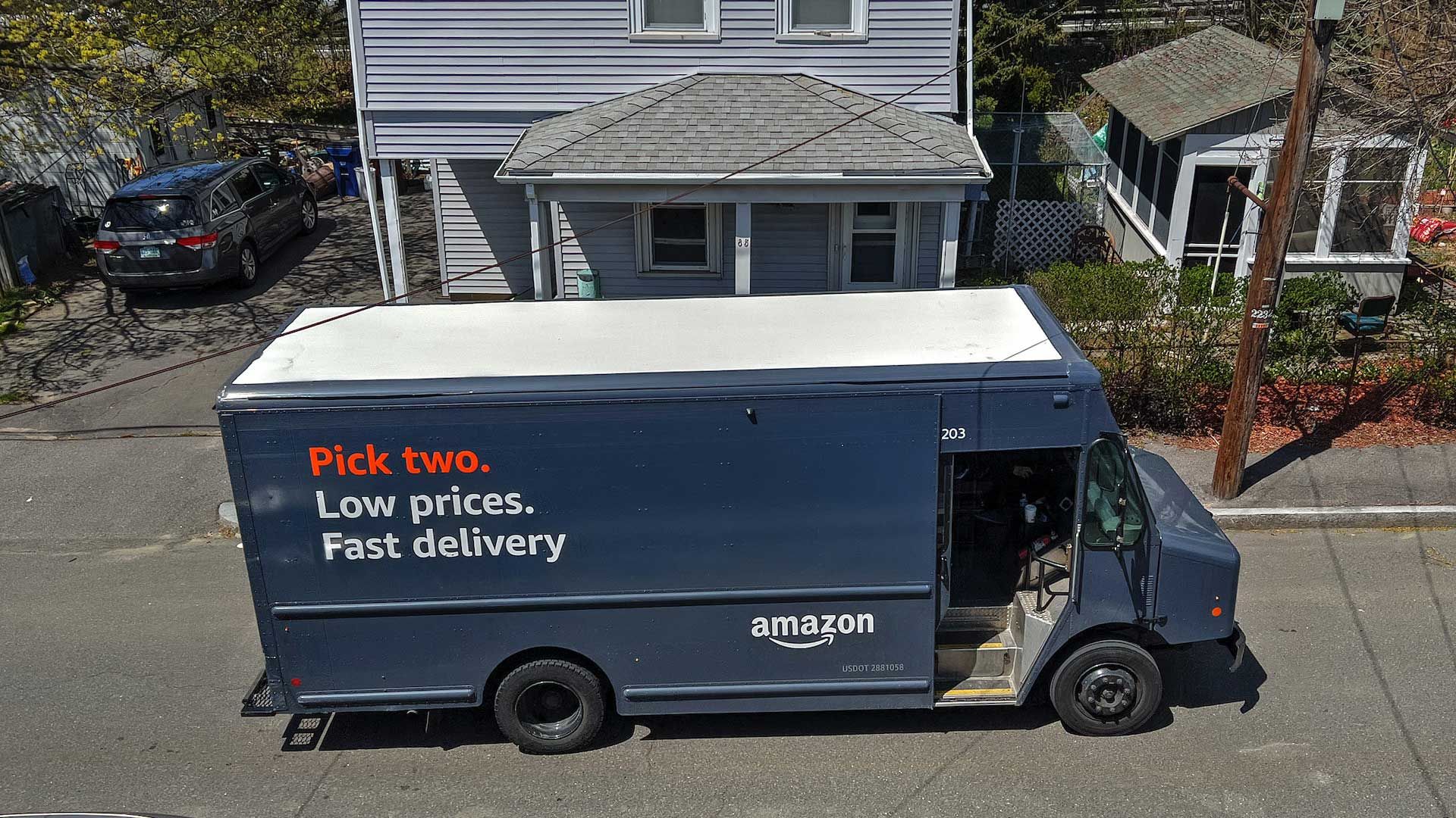 Um caminhão Amazon azul está estacionado do lado de fora de uma casa cinza