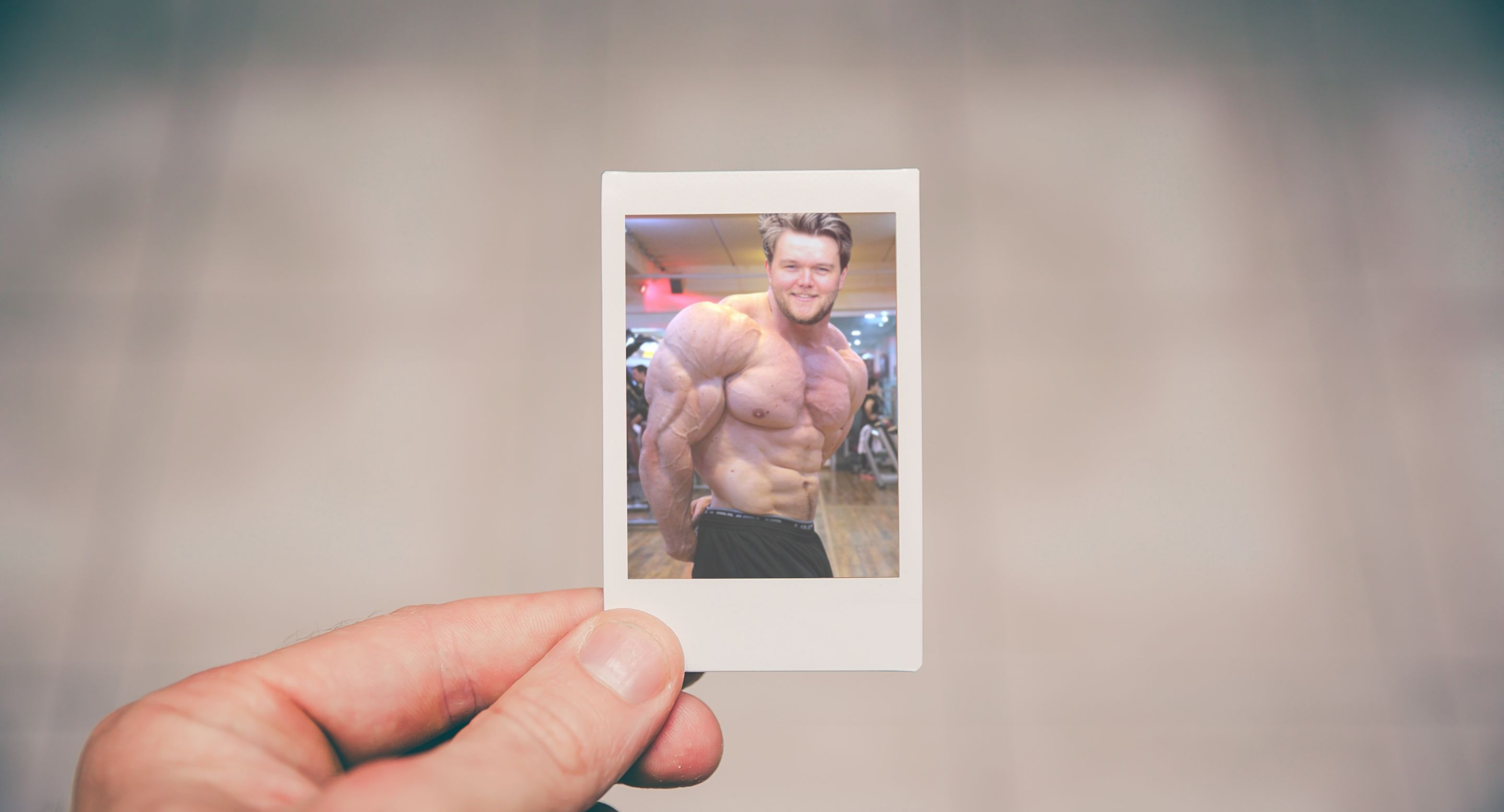 A hand holding a photo of a body builder