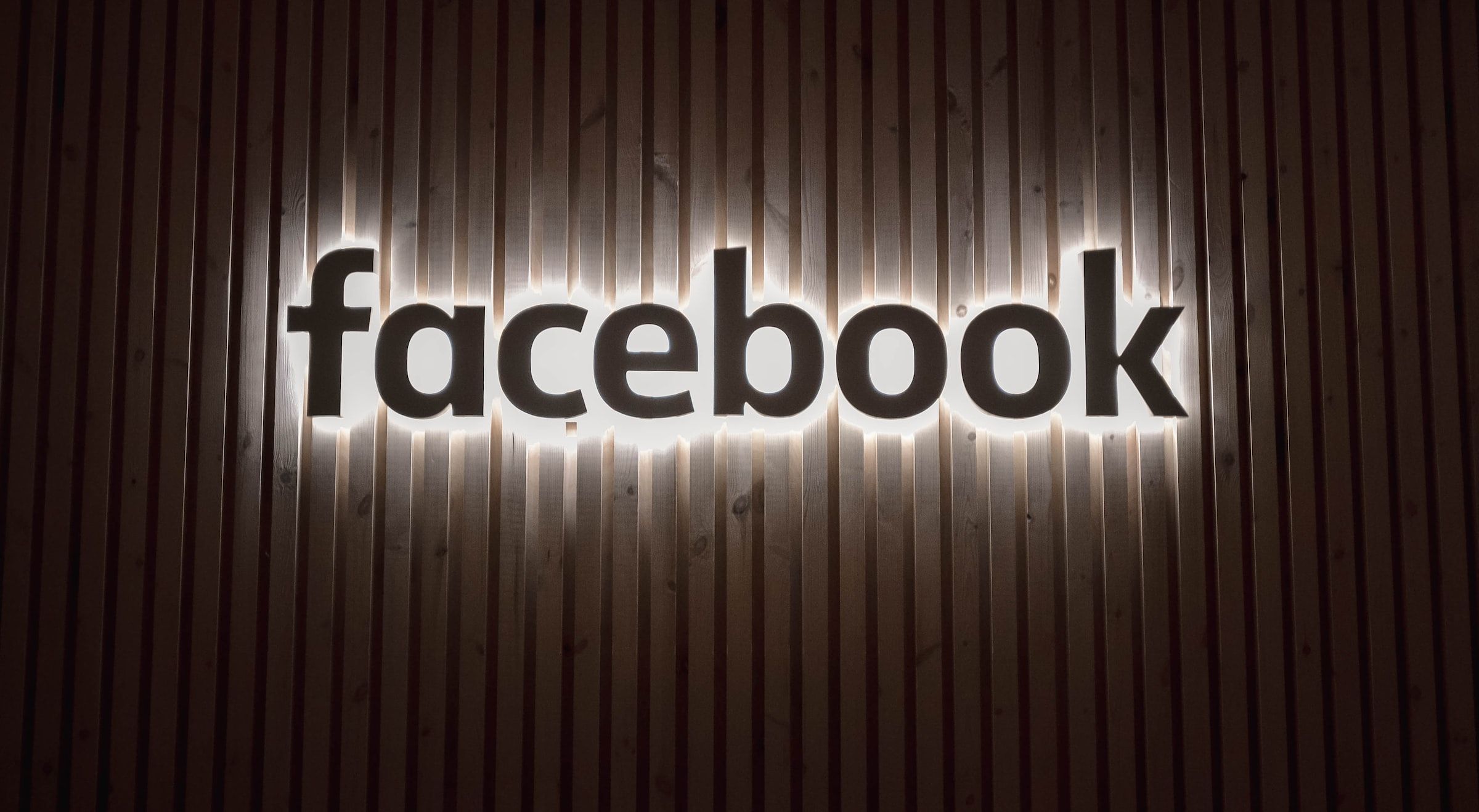 Facebook logo against a wood fence