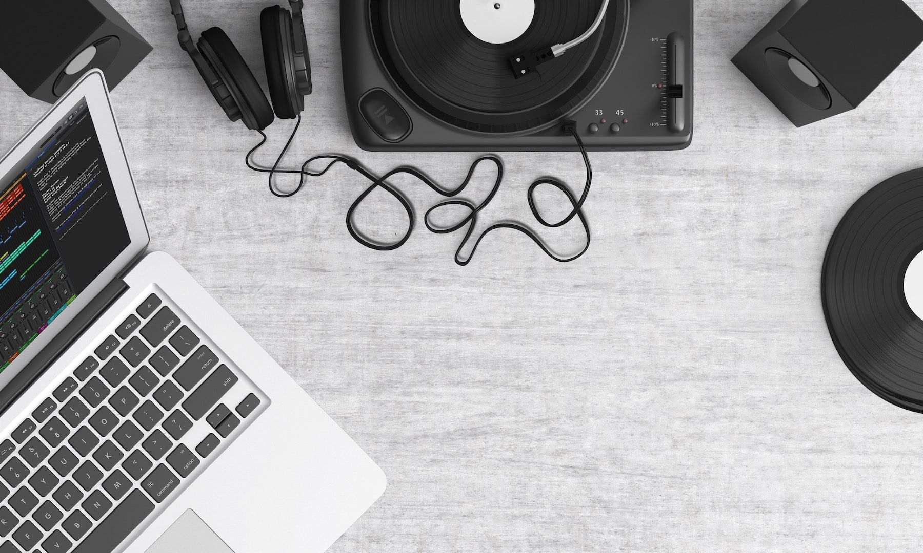A laptop, turntable, and headphones sit on a gray table.