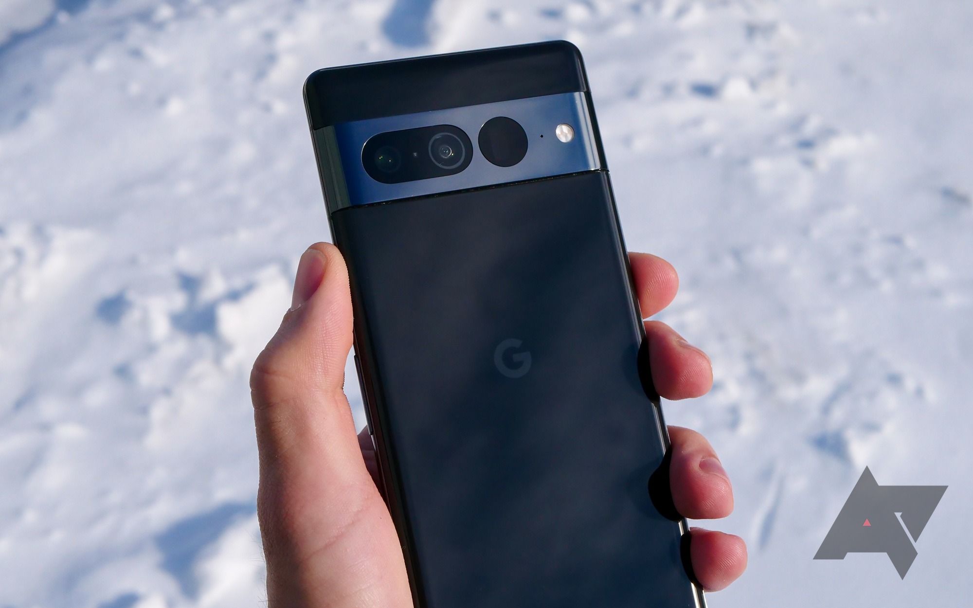 A person holds a black Google Pixel 7 Pro above snow. 