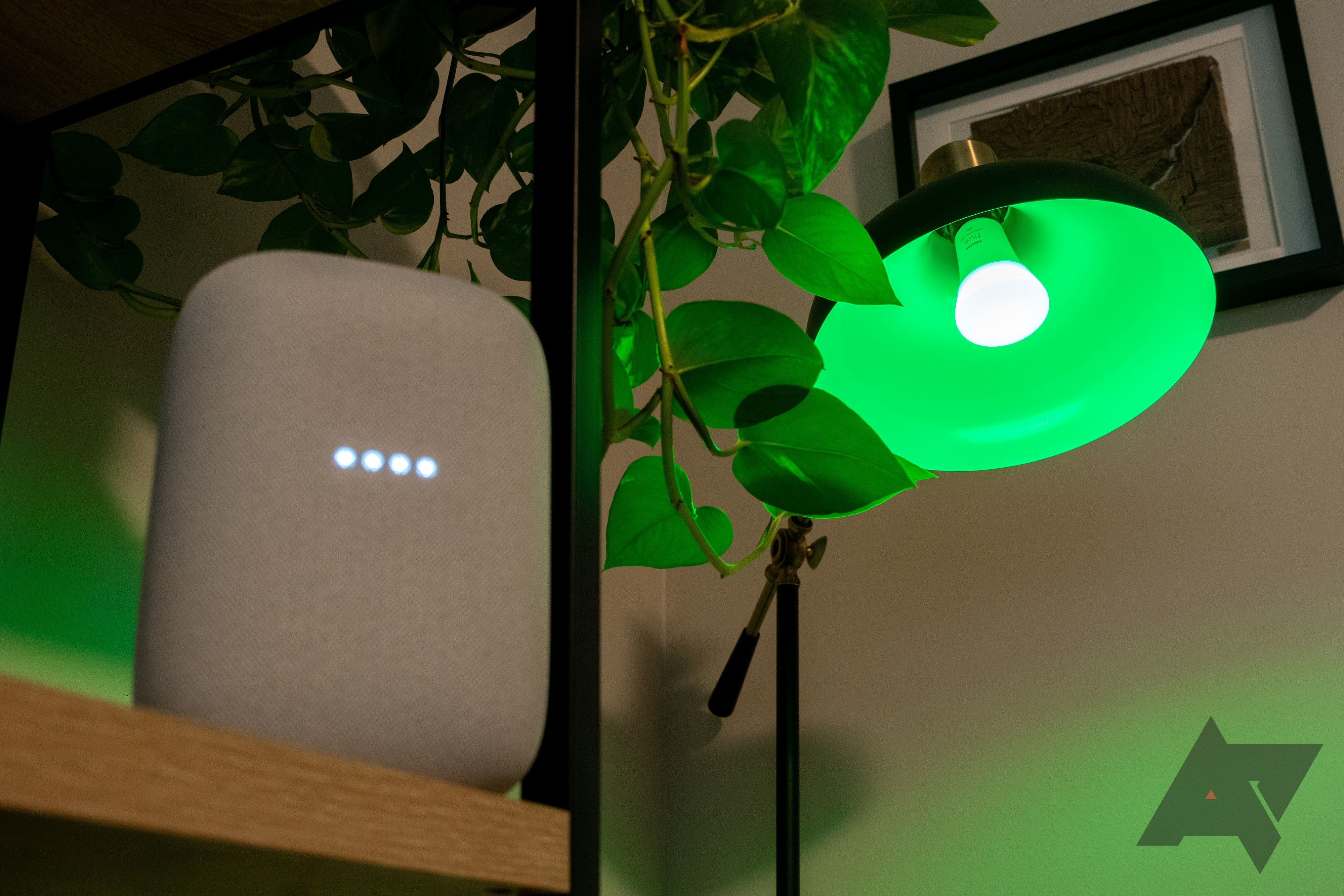 A green Phillips Hue bulb next to an Amazon Nest speaker