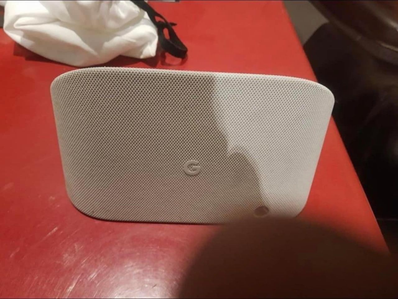 A leaked image reportedly of the Google Pixel Tablet dock. The dock is covered in light fabric and sits on a red table