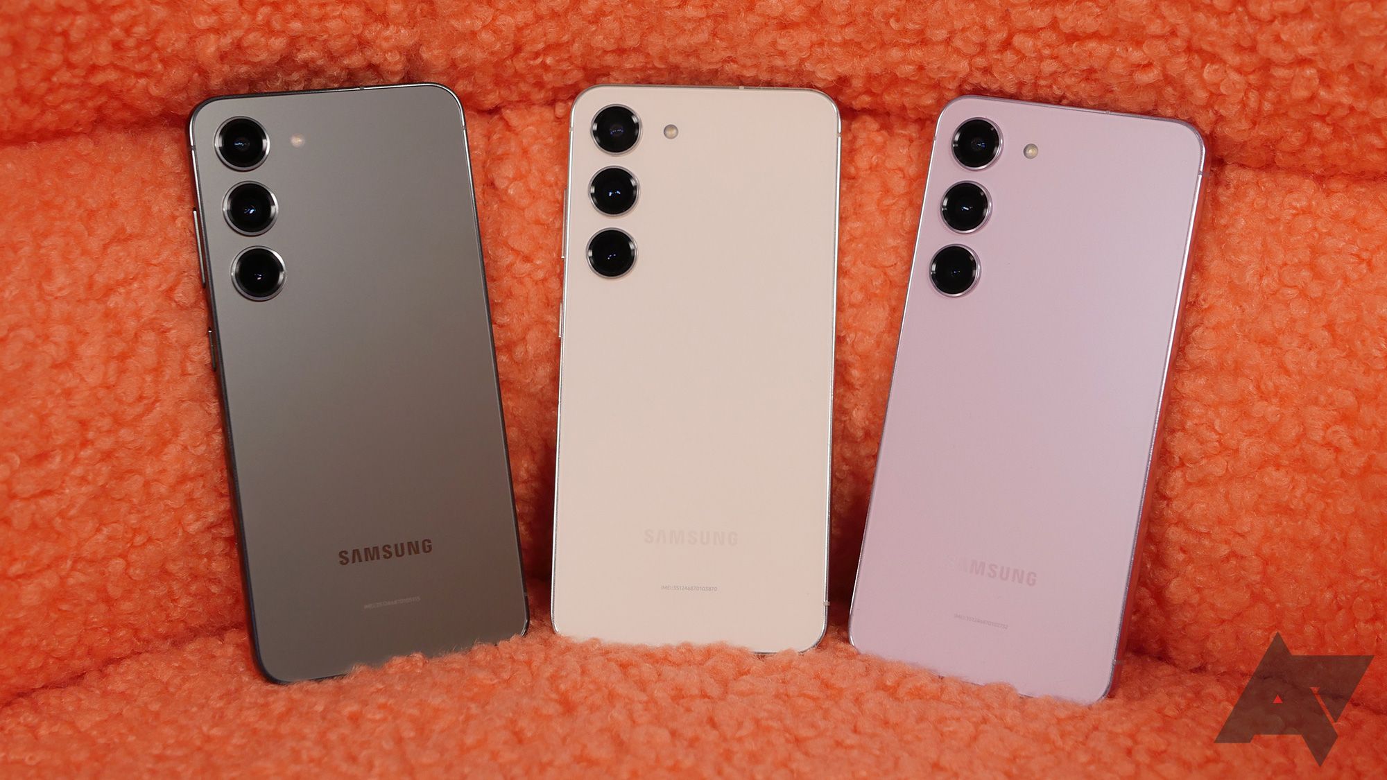 Three Samsung Galaxy S23 phones against an orange background