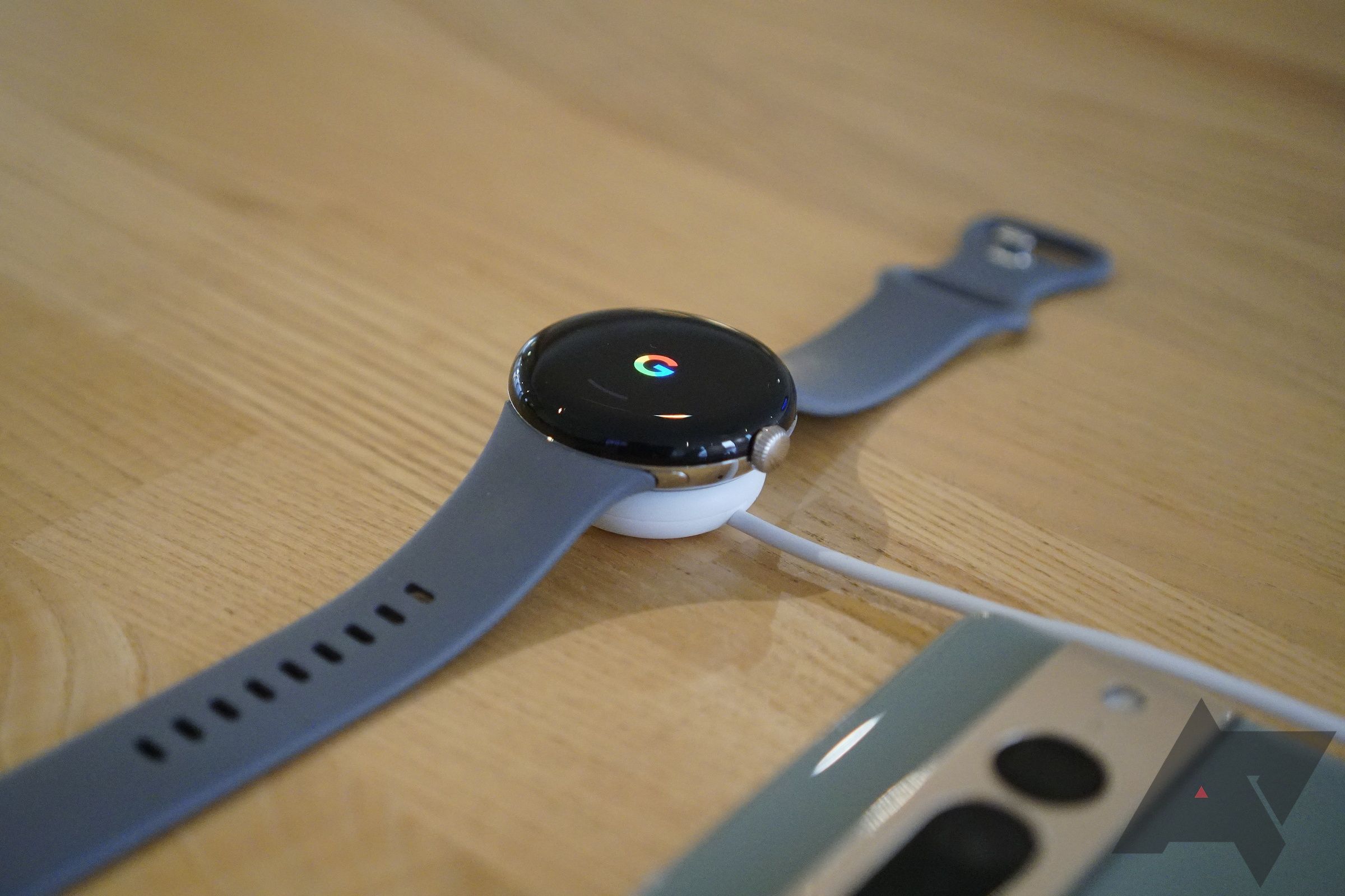 A smartwatch charging on a desk next to a smartphone.