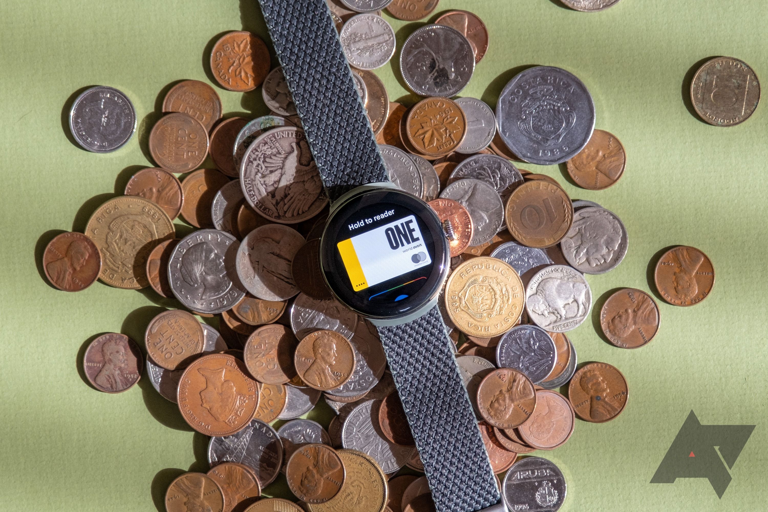 A smartwatch sitting on a pile of coins.