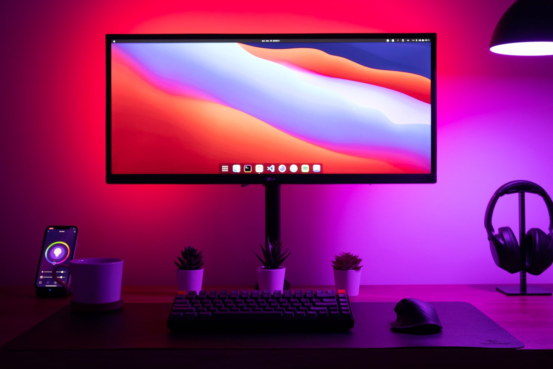 Bright smart light colors bouncing off wall behind computer monitor on modern home office desk.