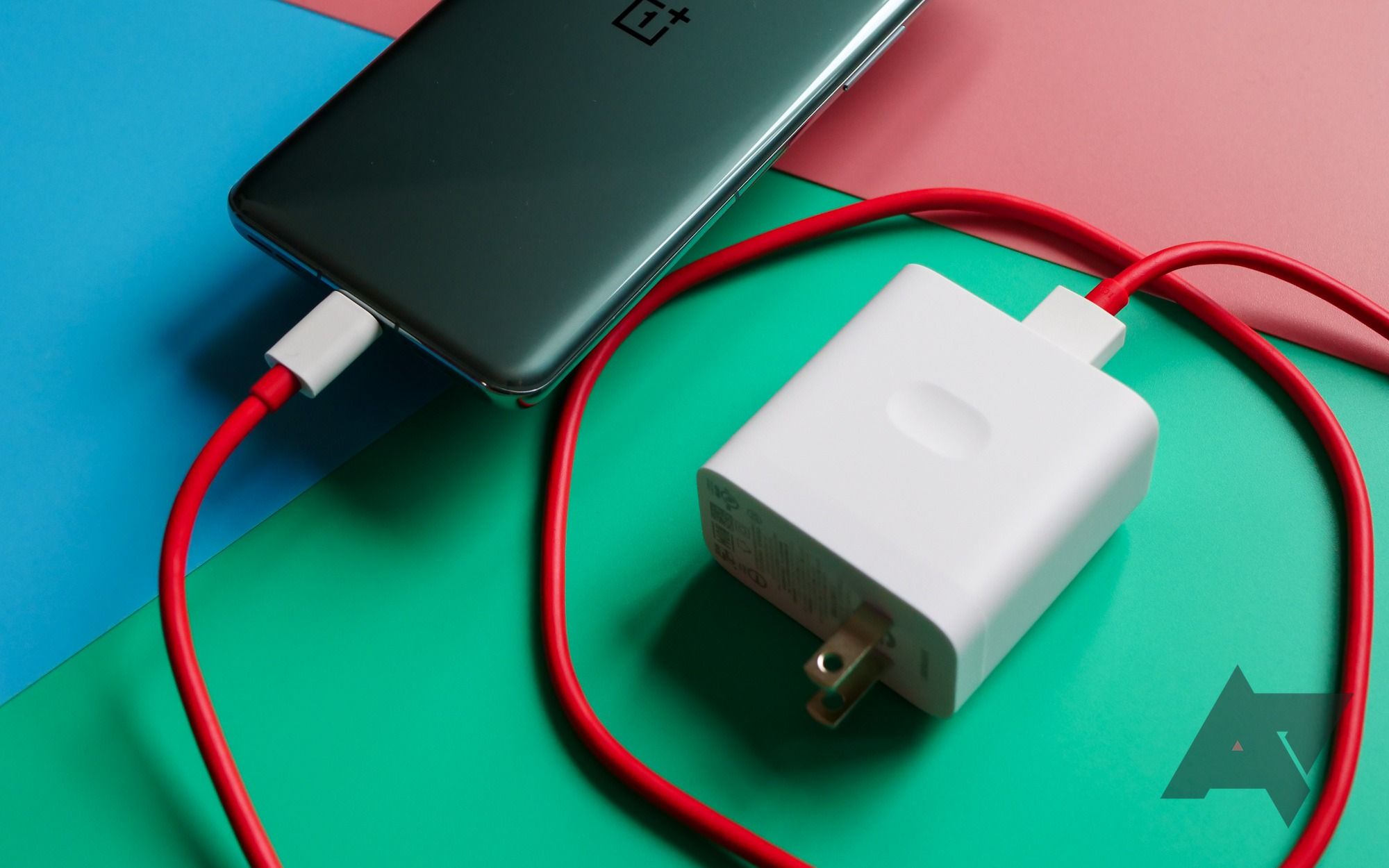 A OnePlus 11 smartphone connected to a charging cable