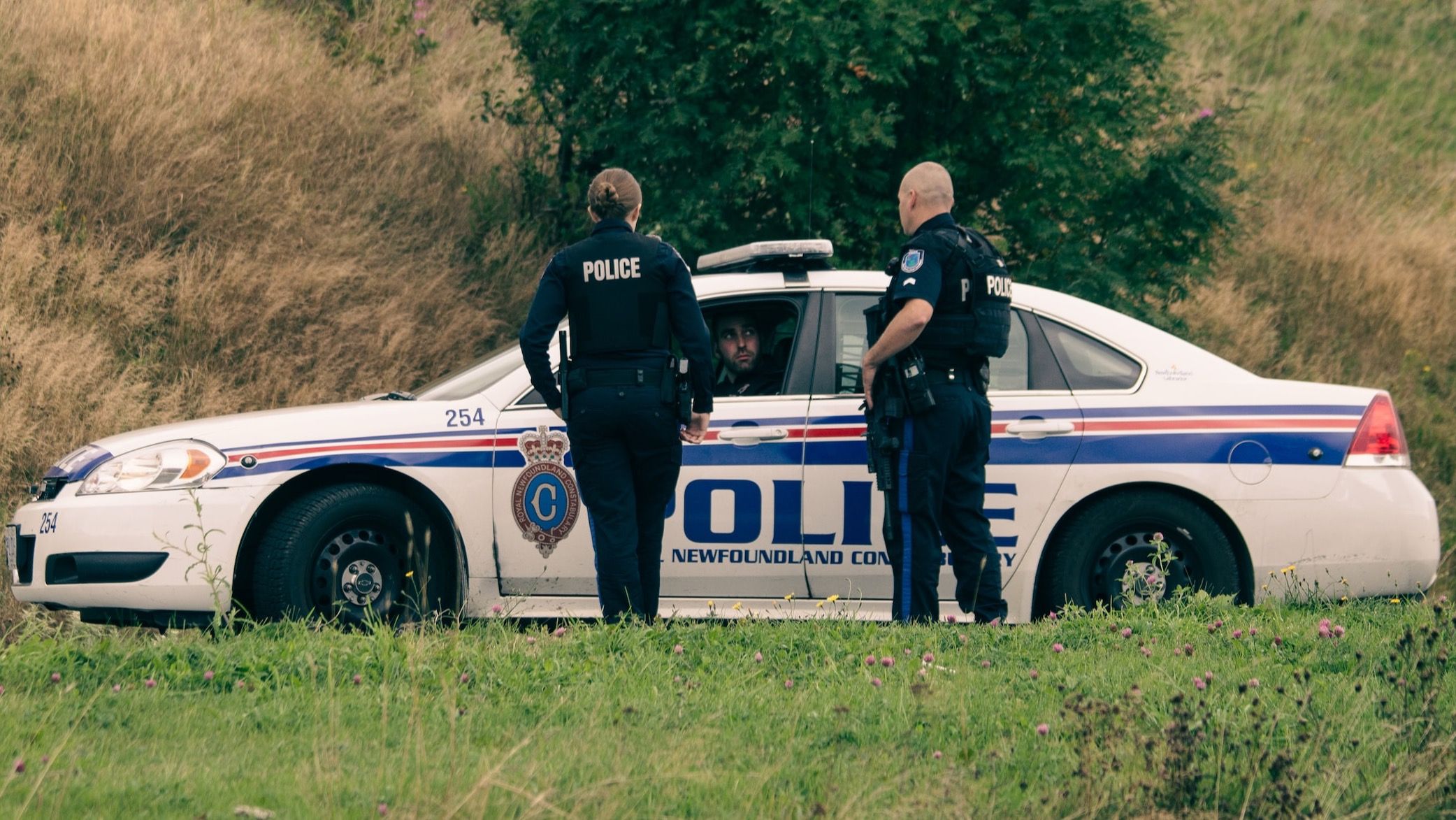 Two police officers standing next to a police car