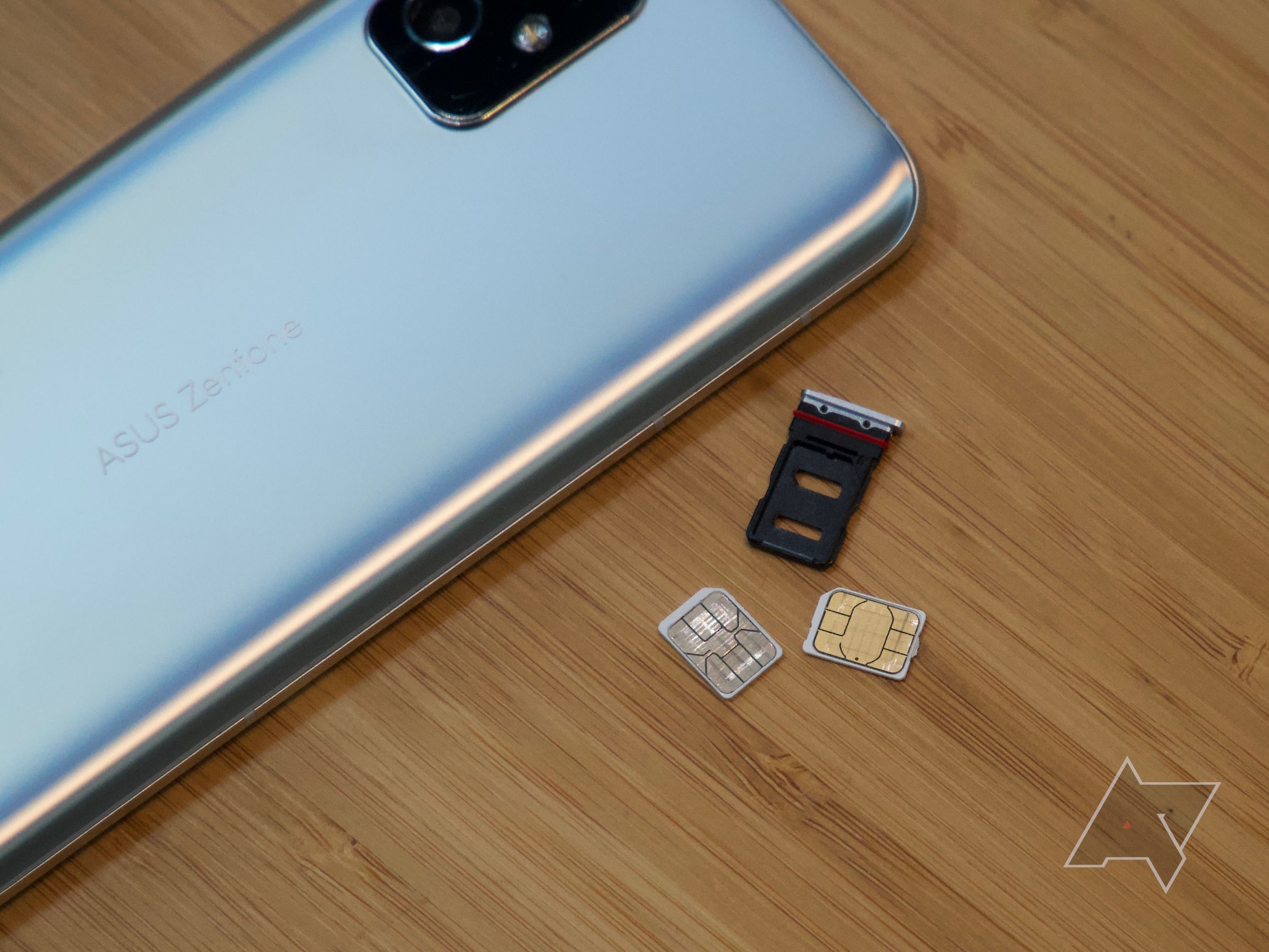 SIM cards next to the SIM tray sitting next to a Zenfone 8