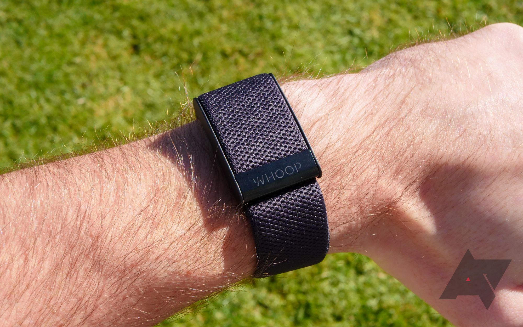 A black Whoop 4.0 tracker being worn on a wrist on a sunny day
